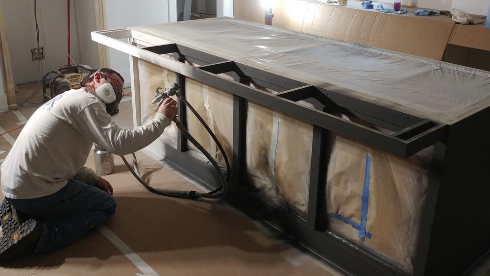 A man wearing a mask is spray painting a table.