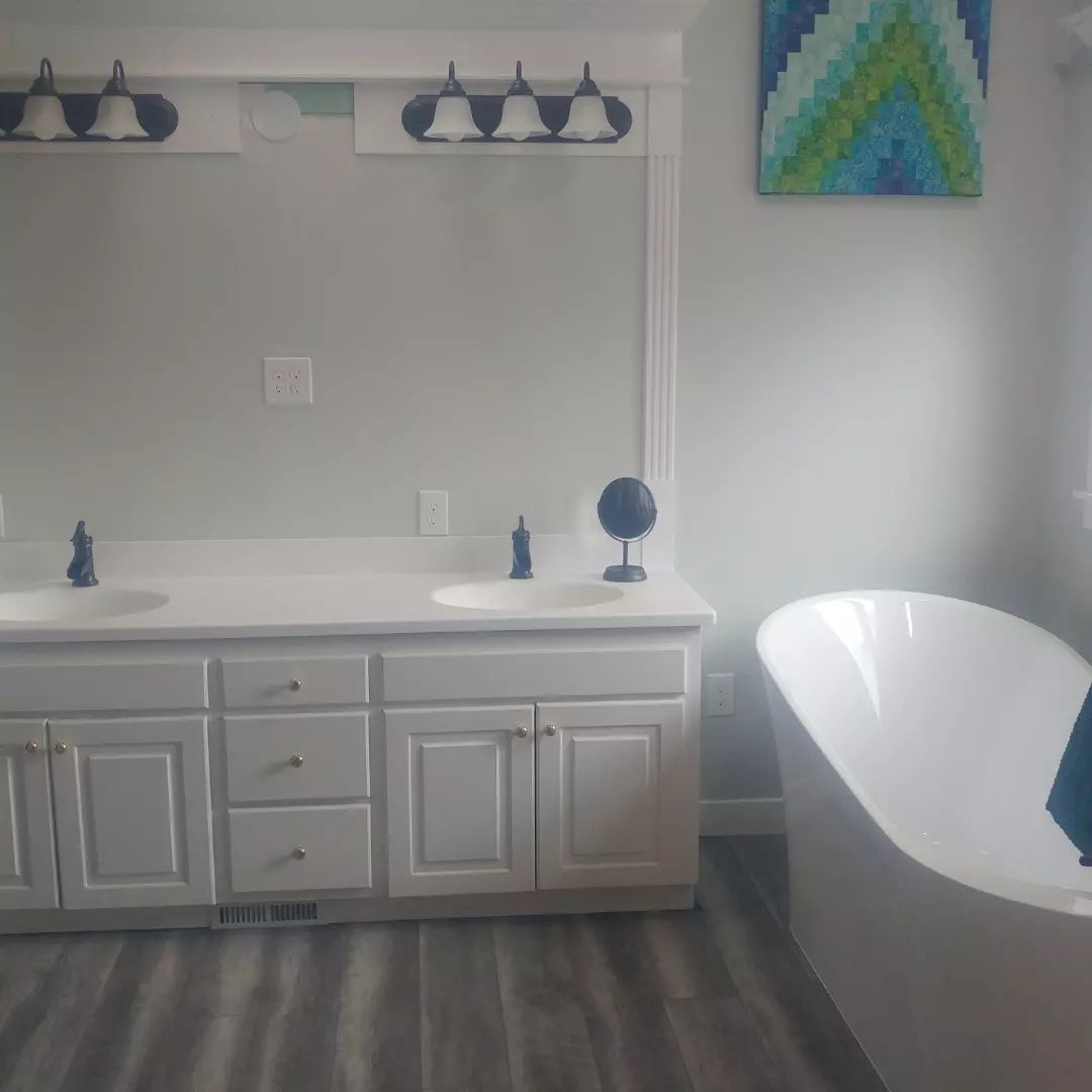 A bathroom with two sinks, a tub and a mirror