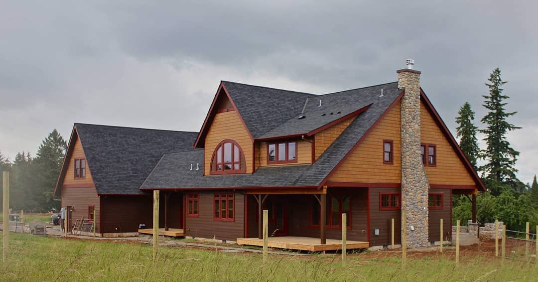 A large wooden house is sitting in the middle of a grassy field