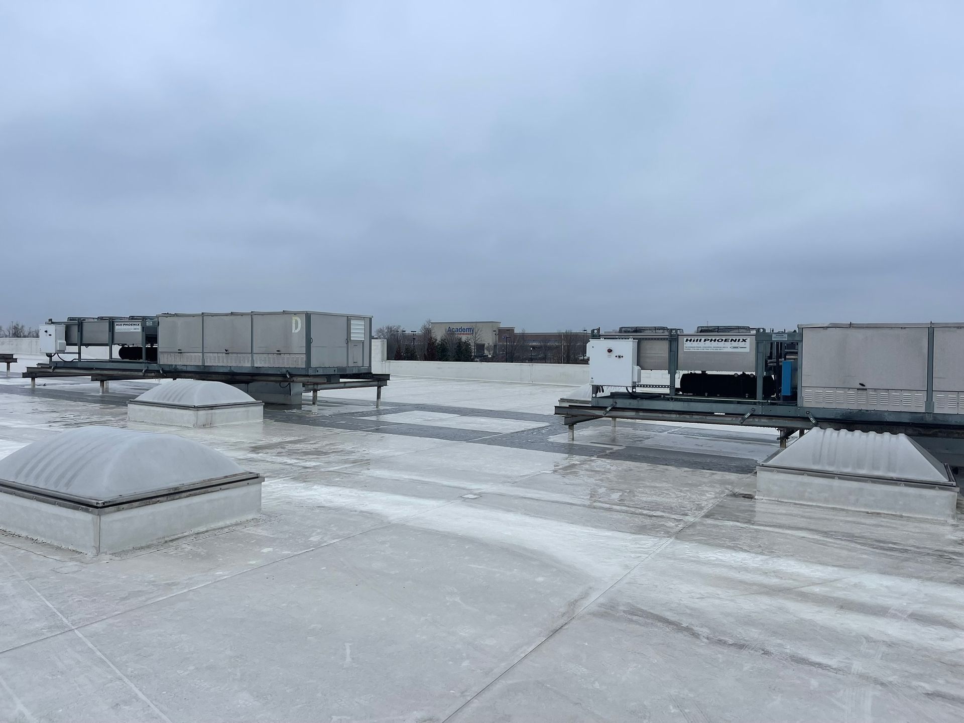 Snow-covered rooftop with HVAC units under a cloudy sky