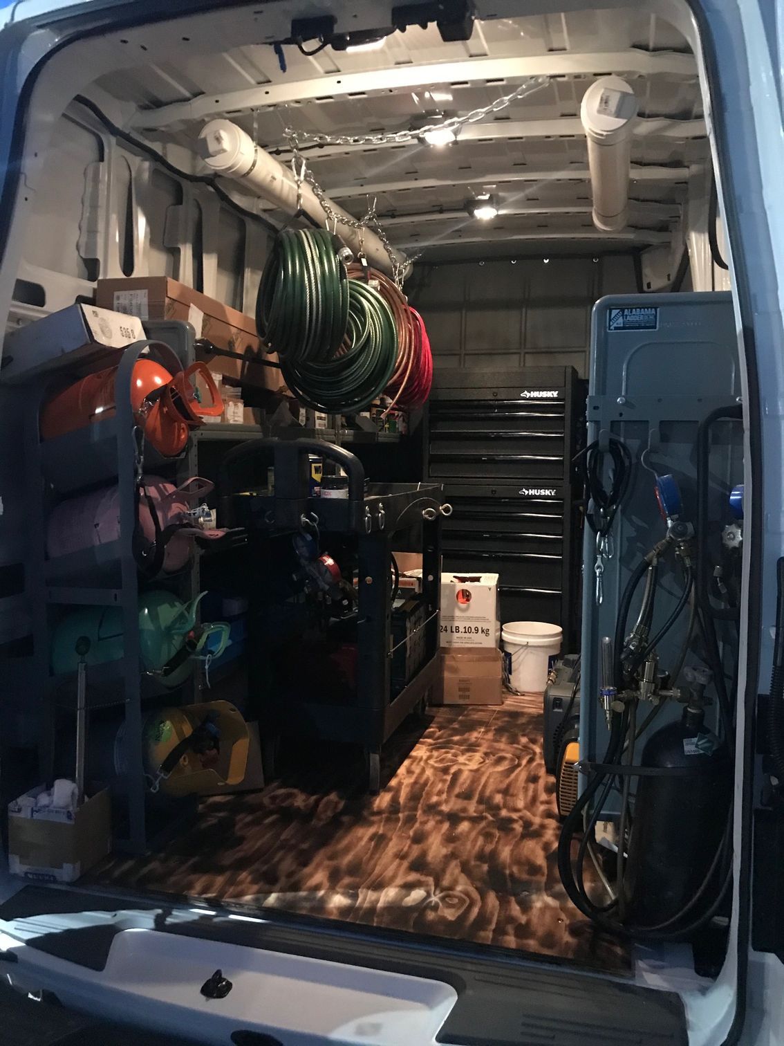 Cargo van interior with tools, coiled hoses, and wooden floor in a work vehicle
