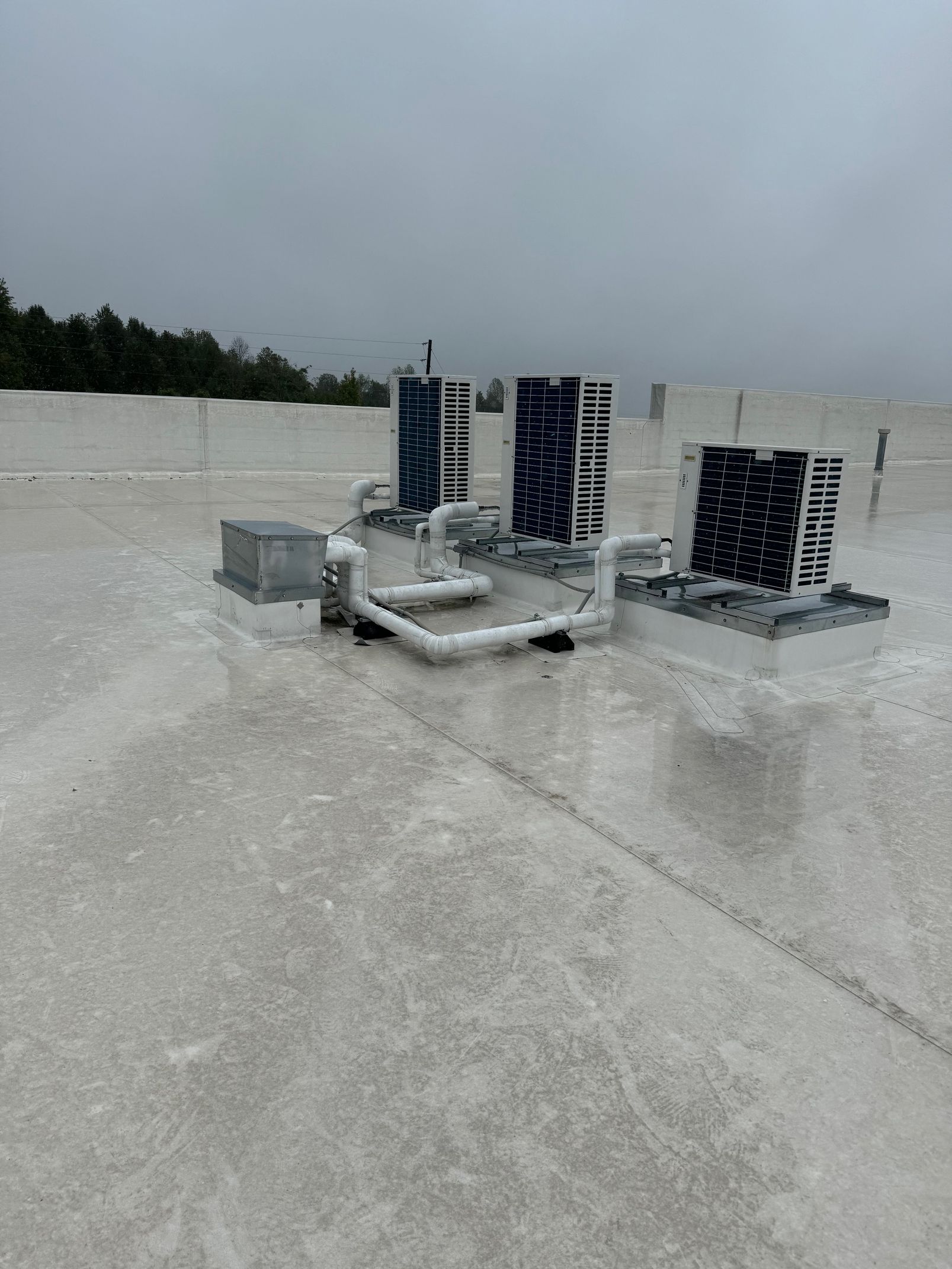 Rooftop HVAC units on a flat white roof under a cloudy sky