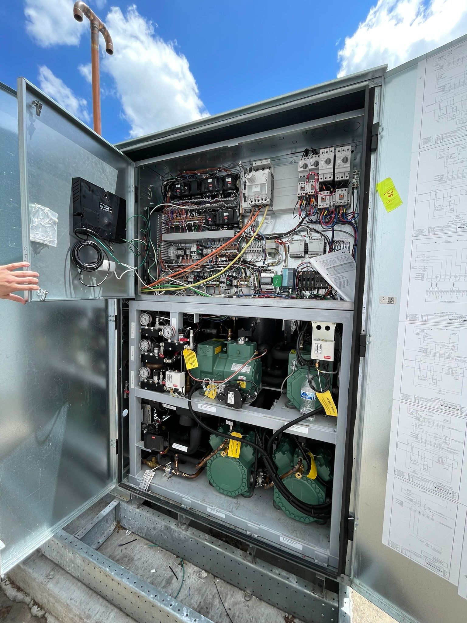 Open electrical control cabinet with exposed wiring and components outdoors