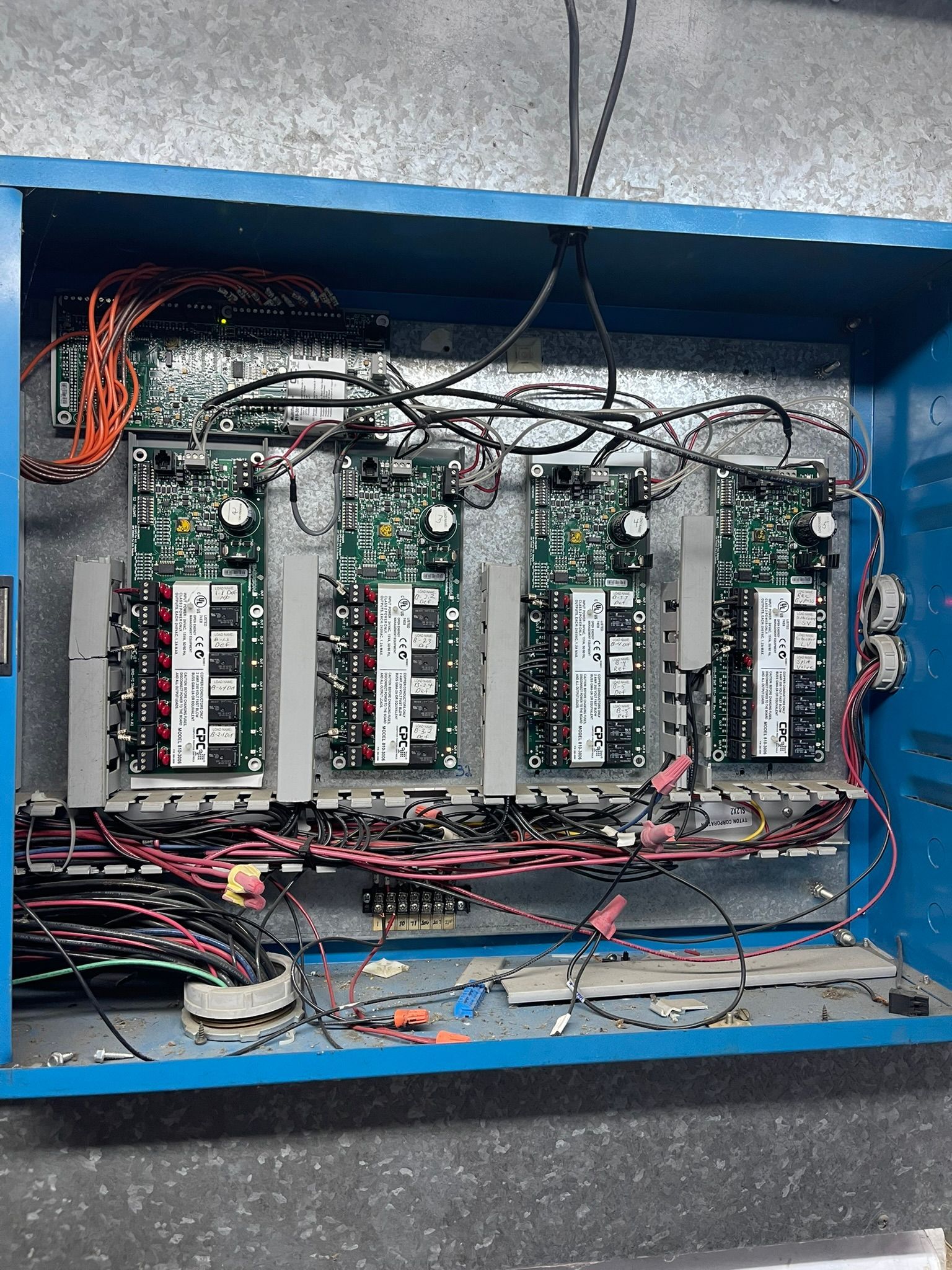 Blue electrical control panel with wiring and four circuit boards inside.