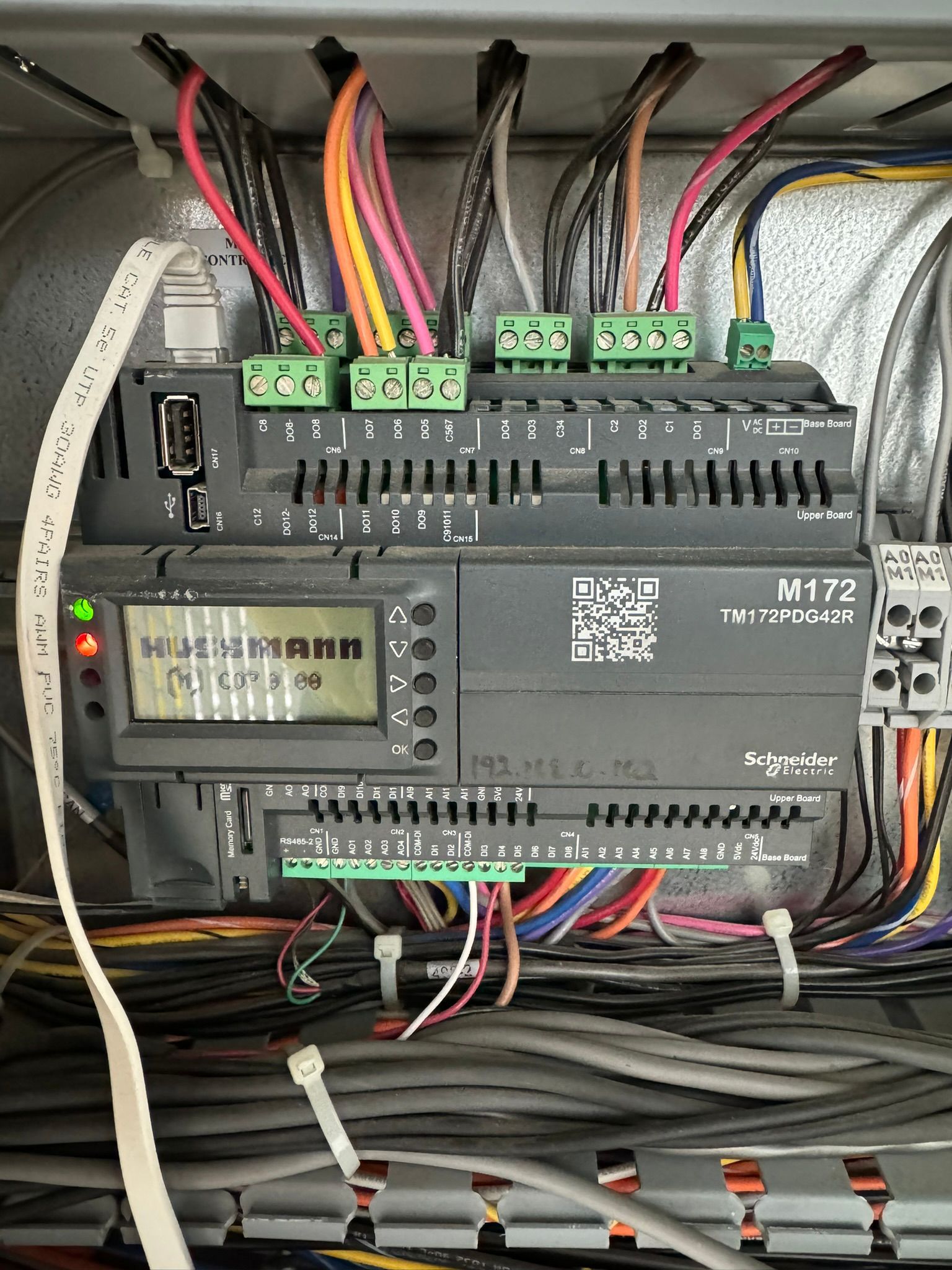 Electrical control panel with PLC modules, wiring, and terminal blocks inside a metal cabinet