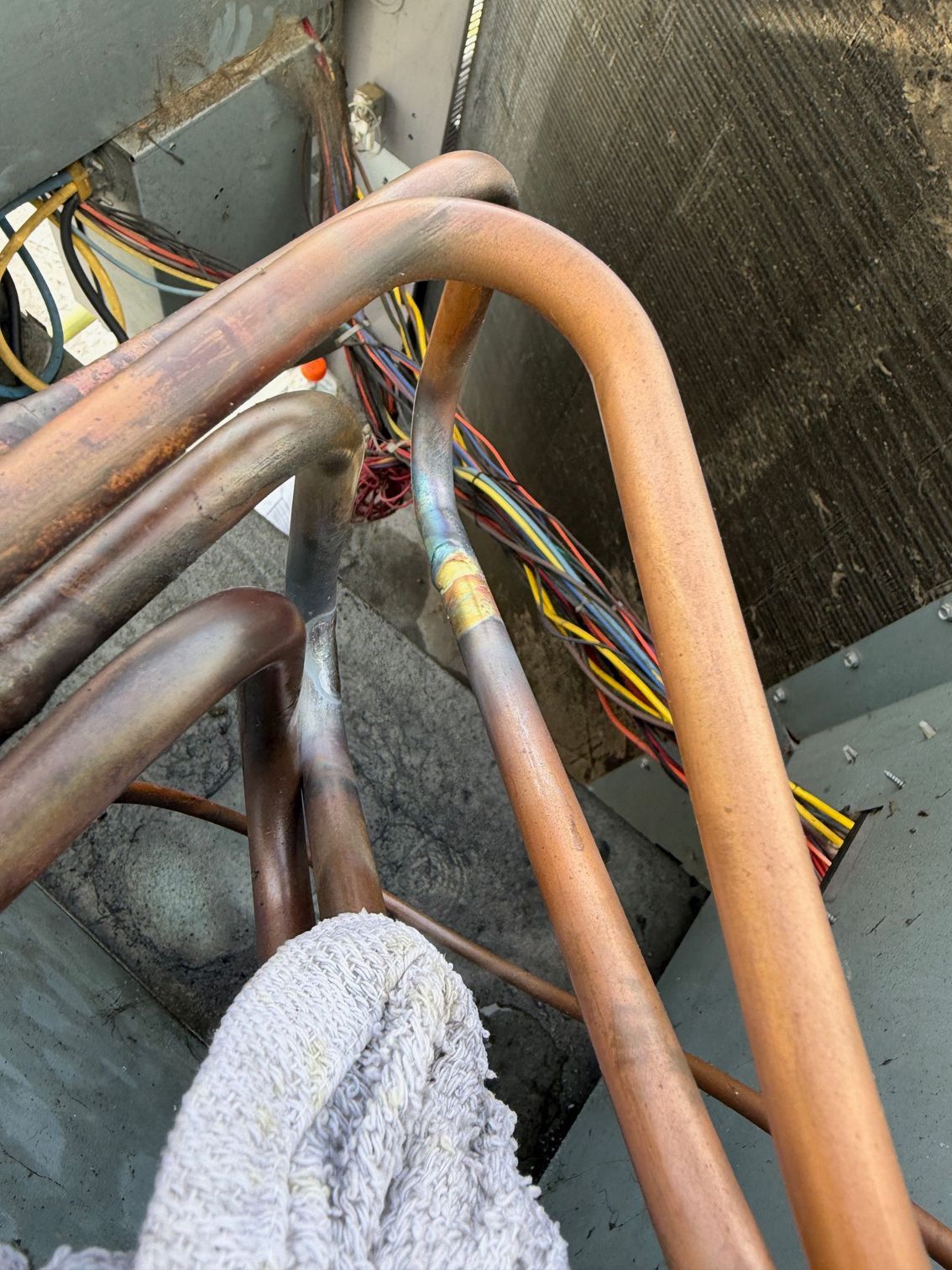 Rusty copper pipes and bundled colorful wires inside a mechanical utility area