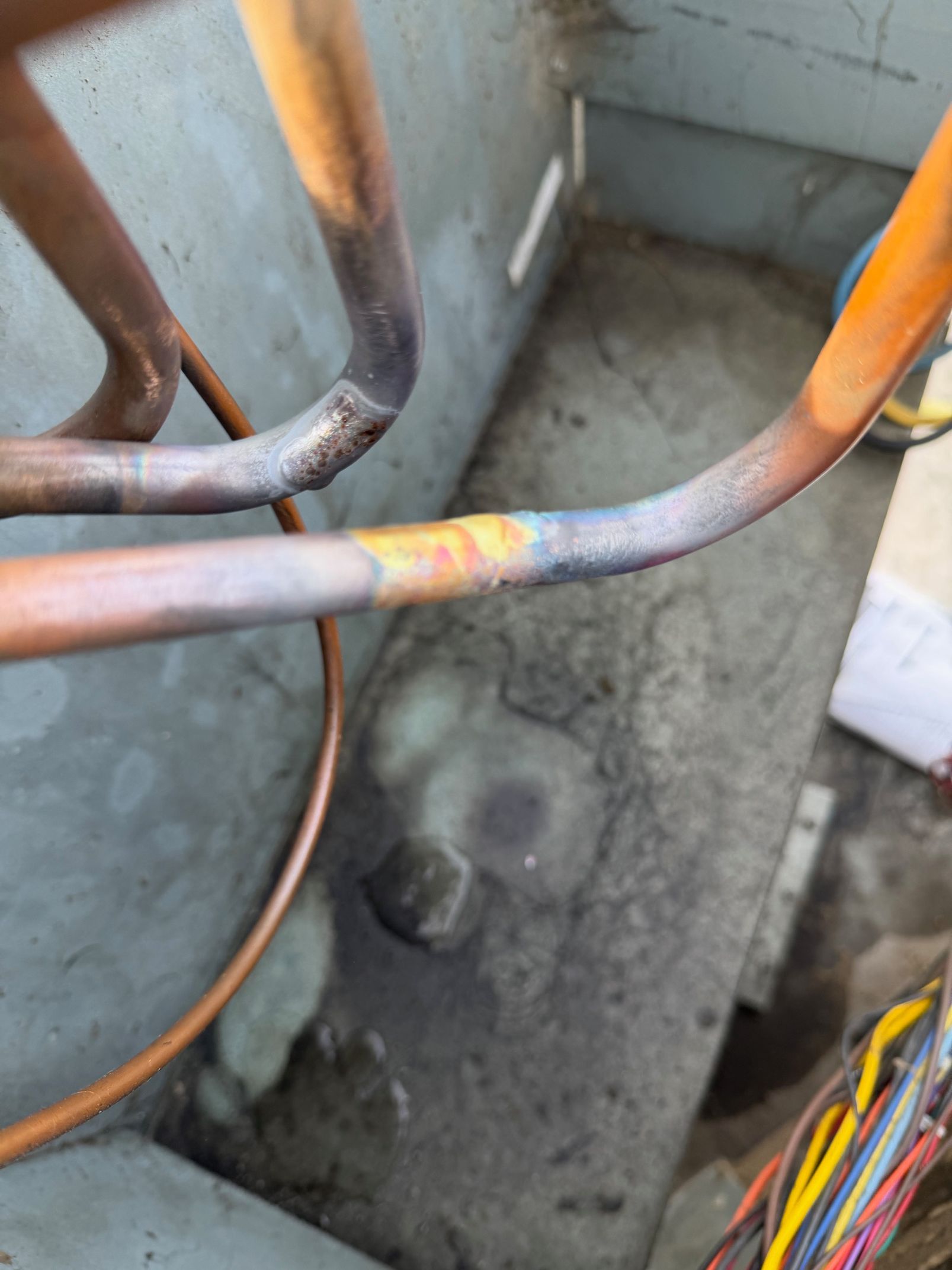 Rusty metal pipes over a stained concrete floor in a small utility area