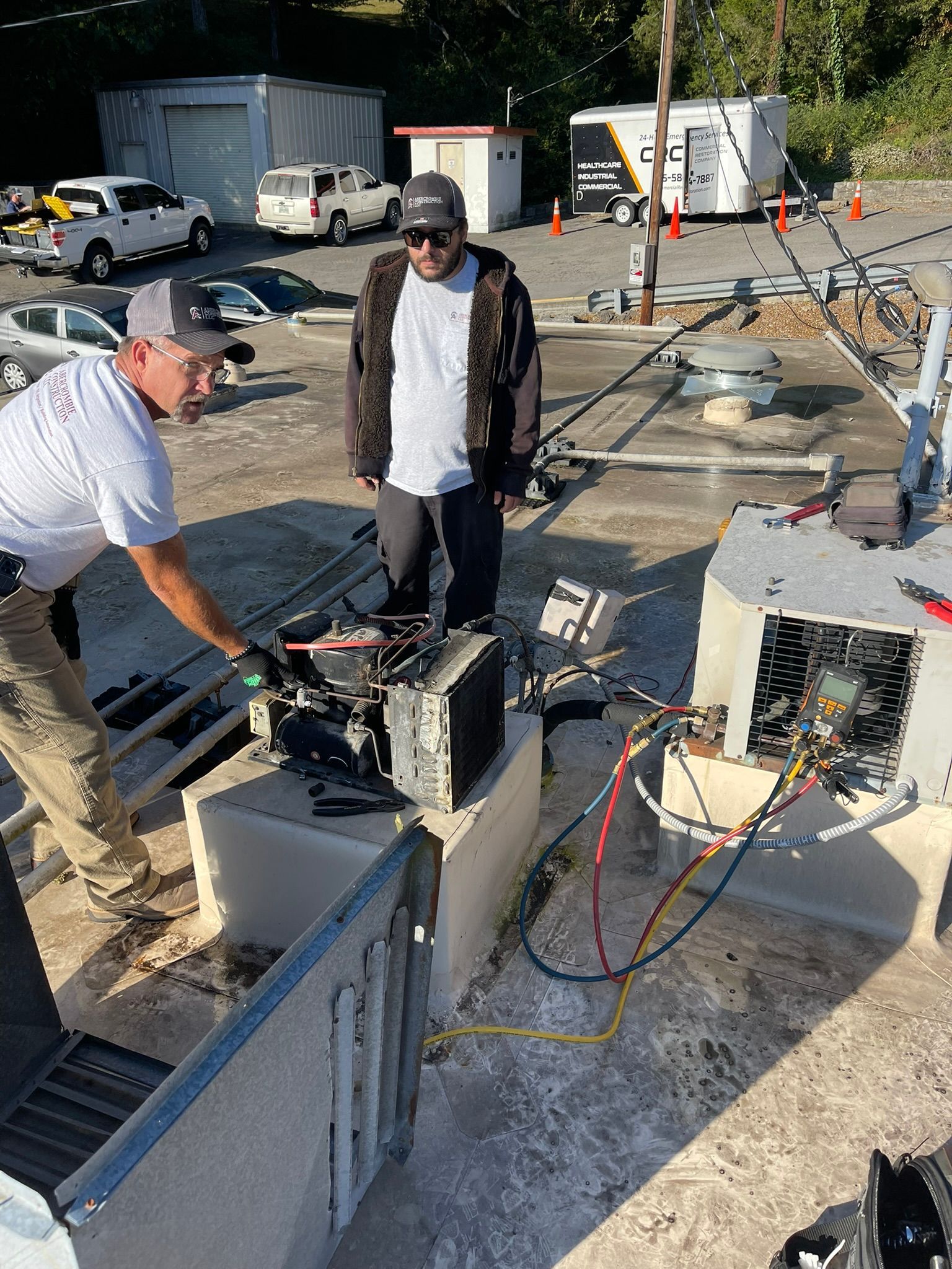 Workers inspecting electrical equipment at a construction site with cables, trailers, and tools nearby