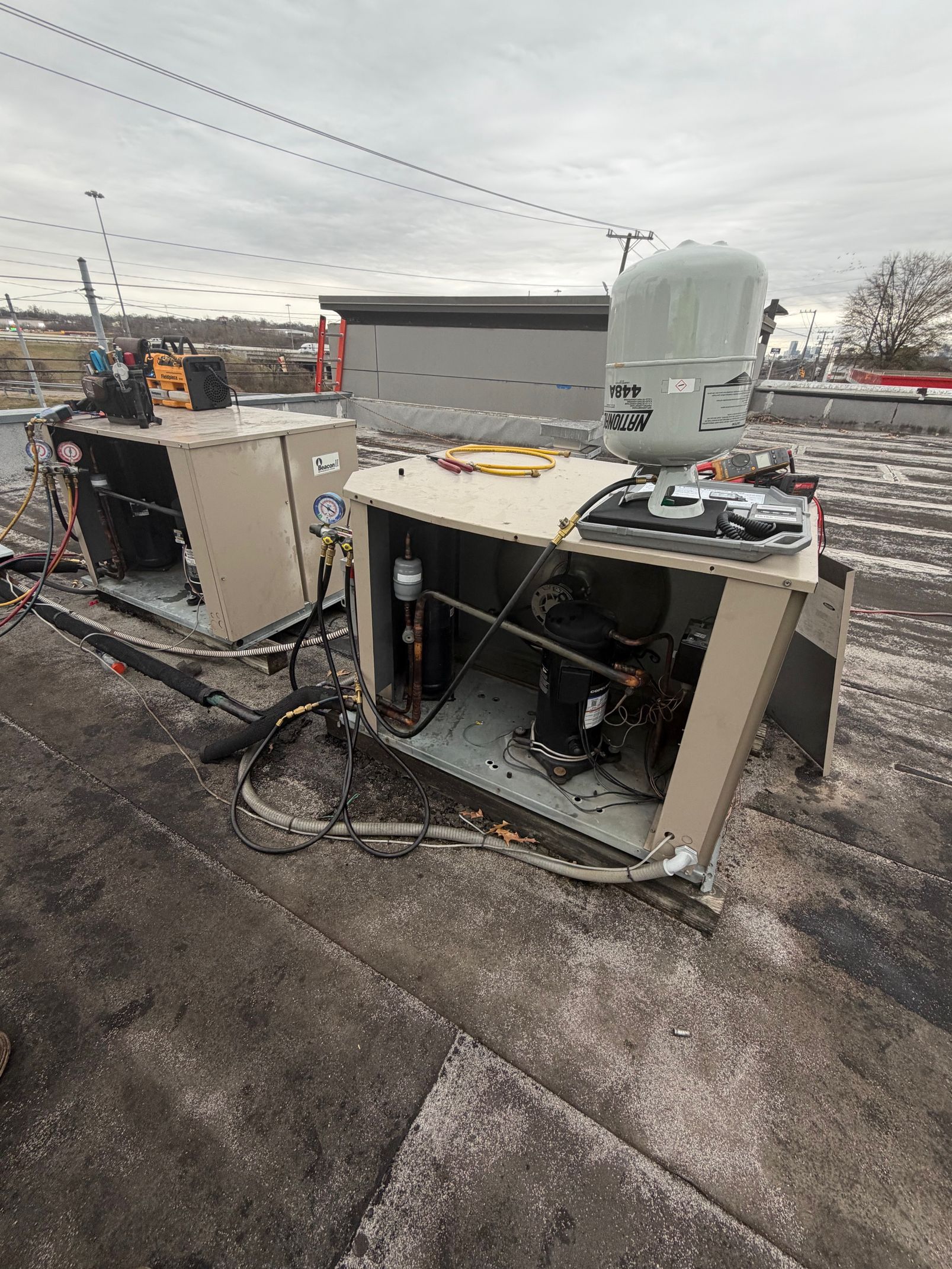 Burned-out rooftop HVAC units with charred debris on a flat roof under a gray sky