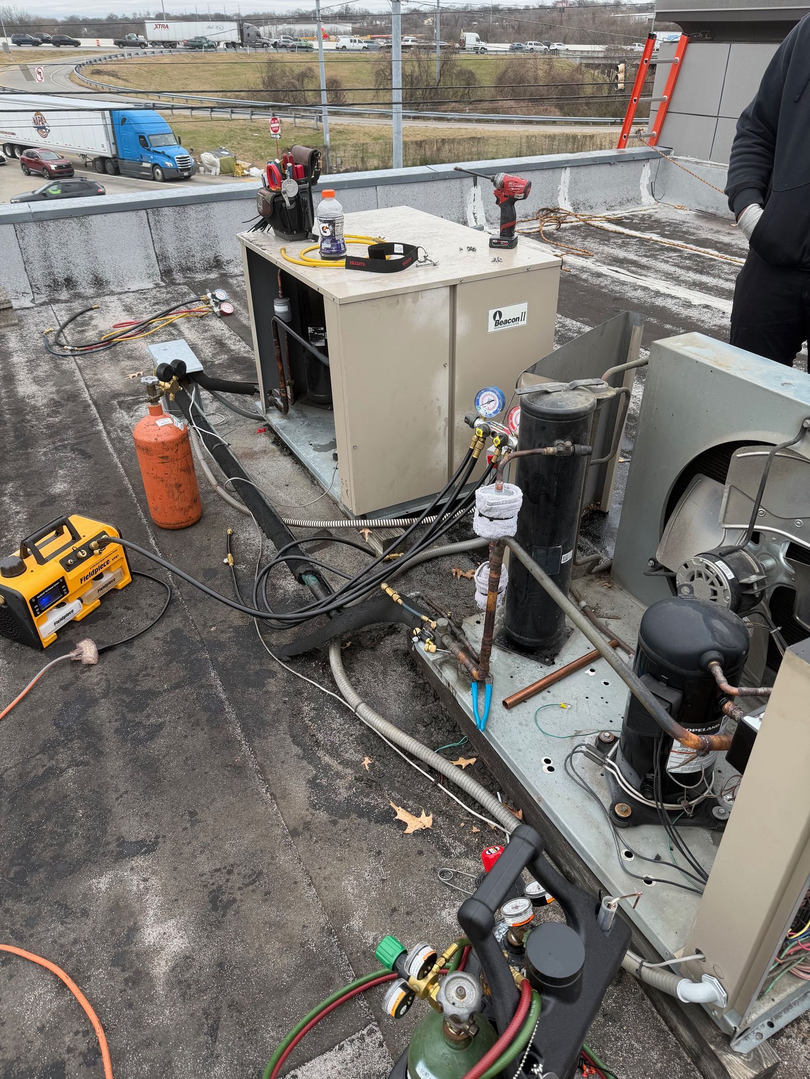 Outdoor industrial equipment with hoses and tools on a rooftop, with workers in the background