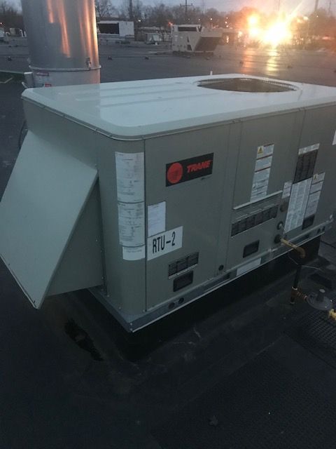Large rooftop HVAC unit at sunset, with bright glare in the background.