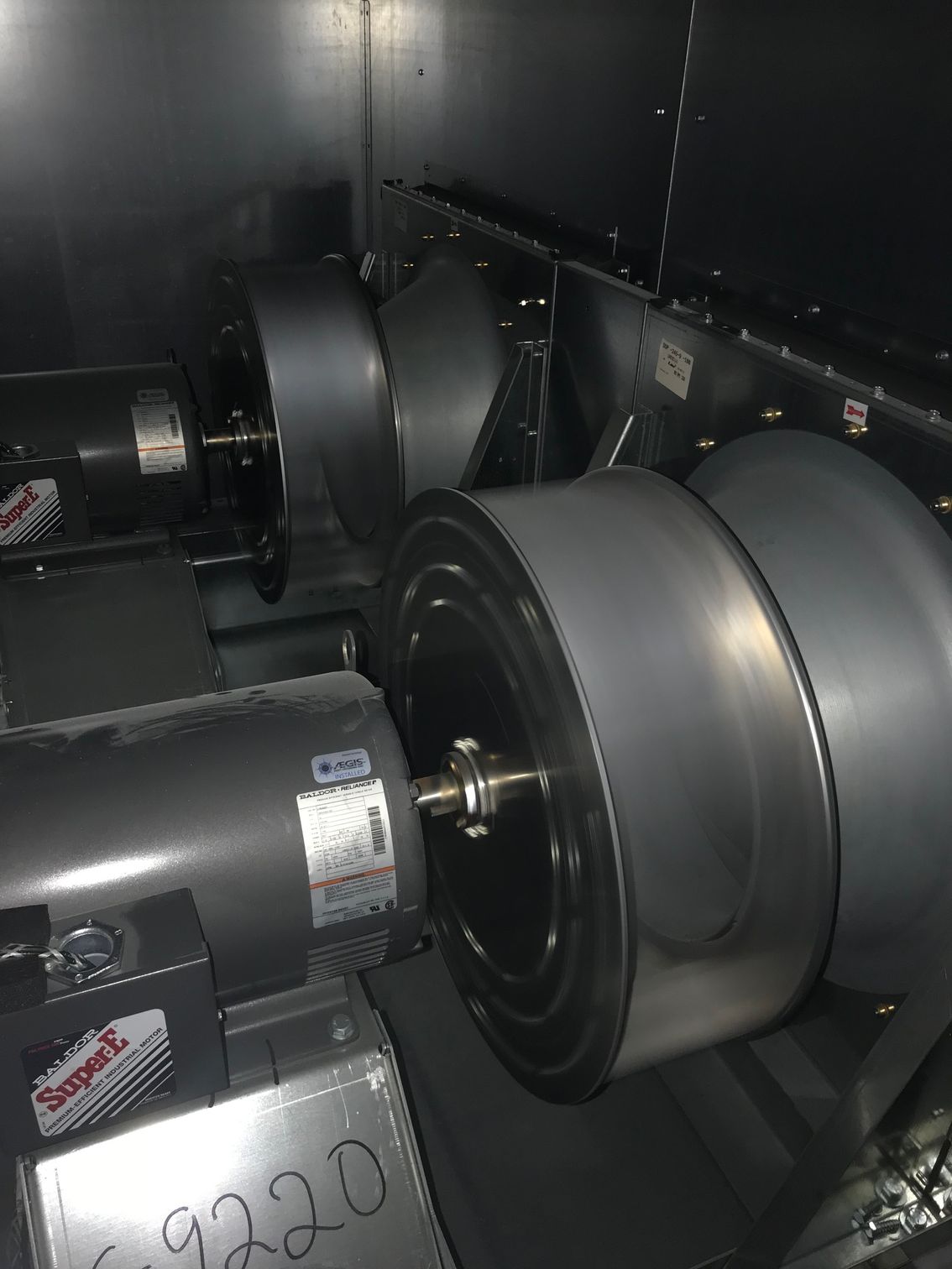 Industrial machinery with large gray metal rollers inside a dark enclosure.