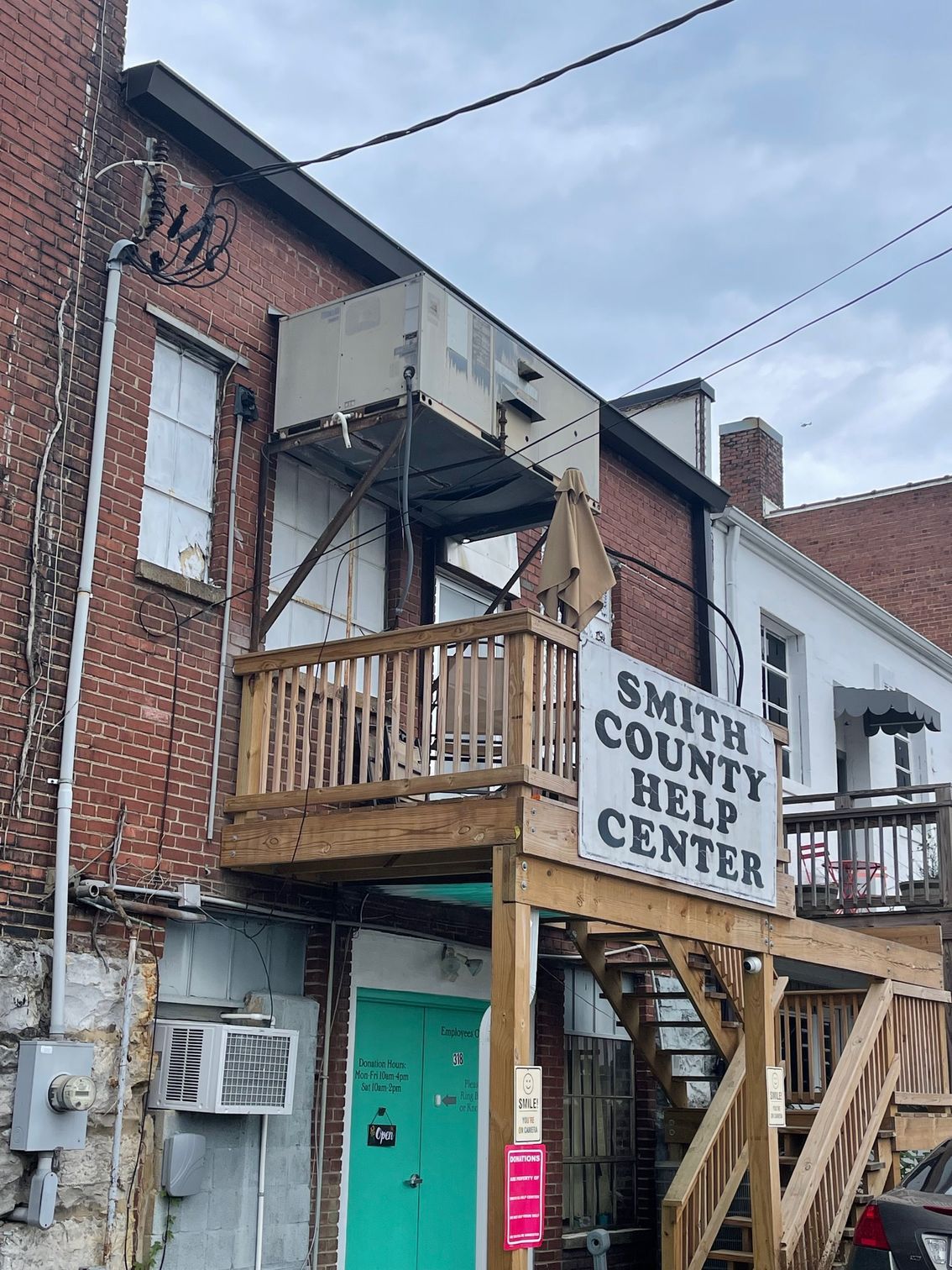 Smith County Help Center sign on a brick building with wooden stairs and teal door