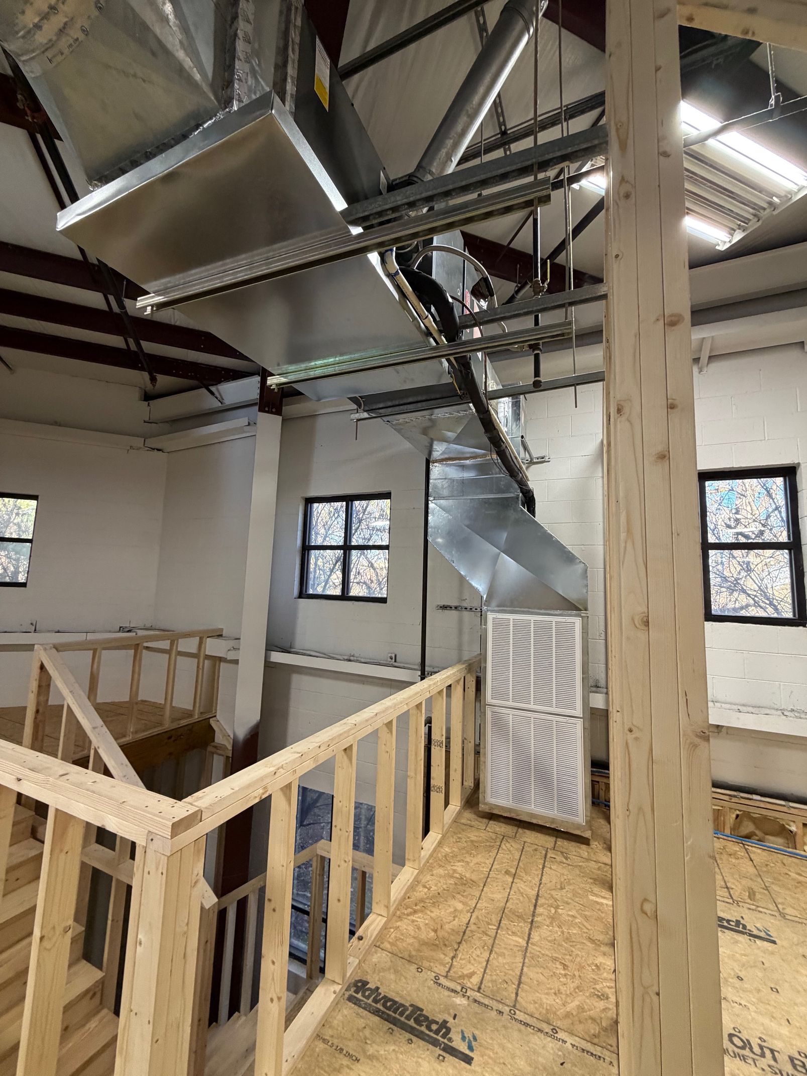 Interior under construction with exposed ducts, wooden framing, and unfinished walls in an industrial space