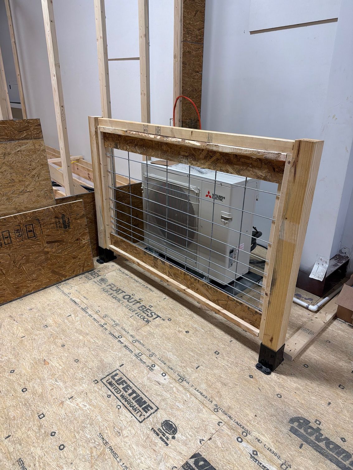 Wood-framed HVAC unit leaning against a wall on a construction subfloor