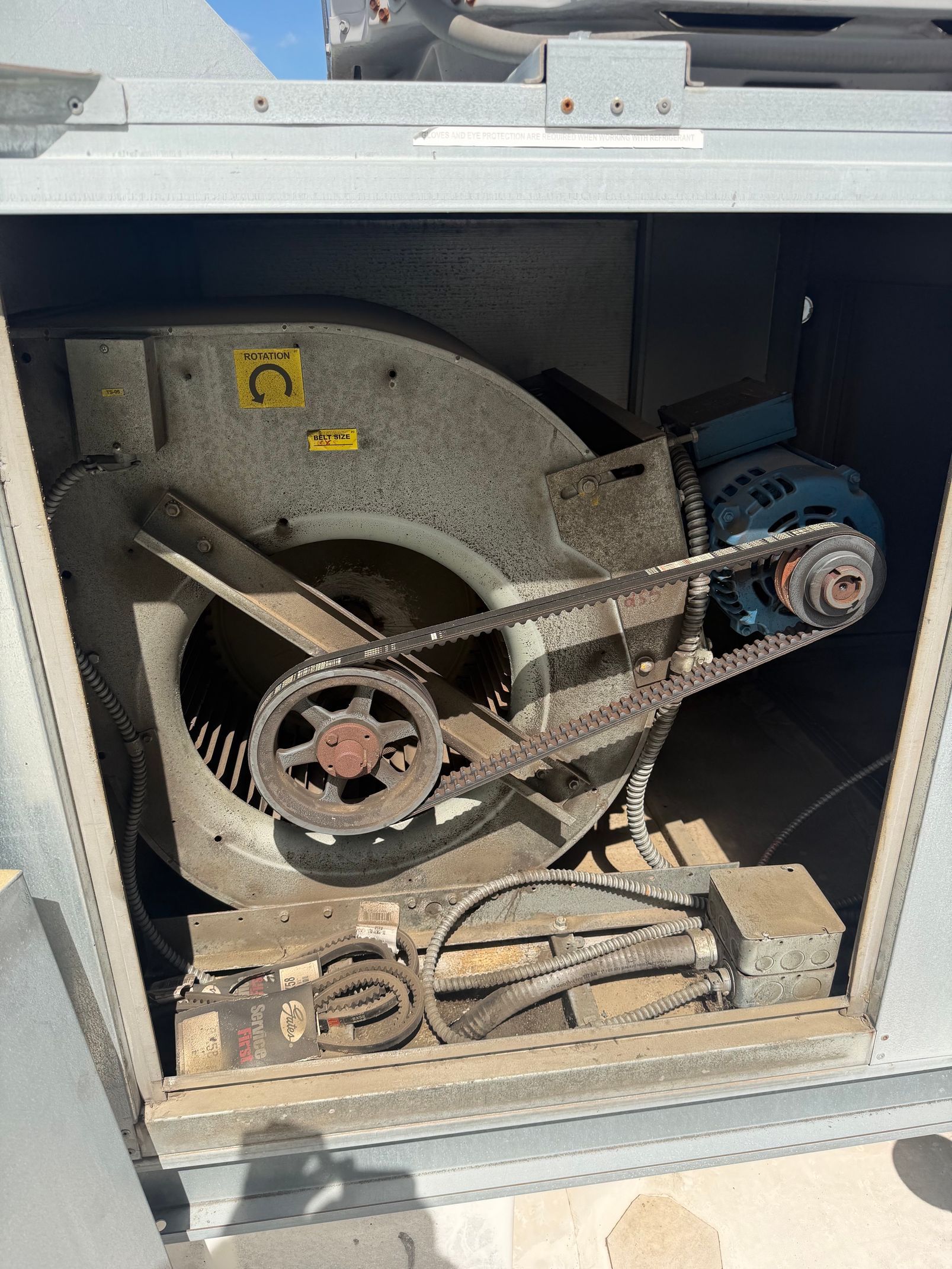 Open machine compartment with belts, pulleys, and wiring inside a metal cabinet.