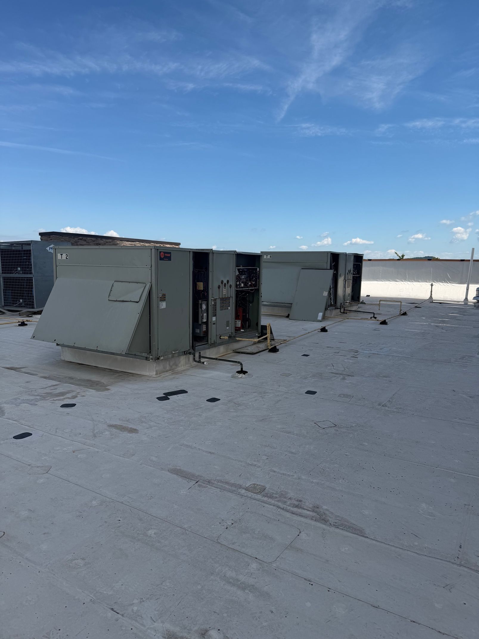 Snow-covered rooftop with large HVAC units under a clear blue sky