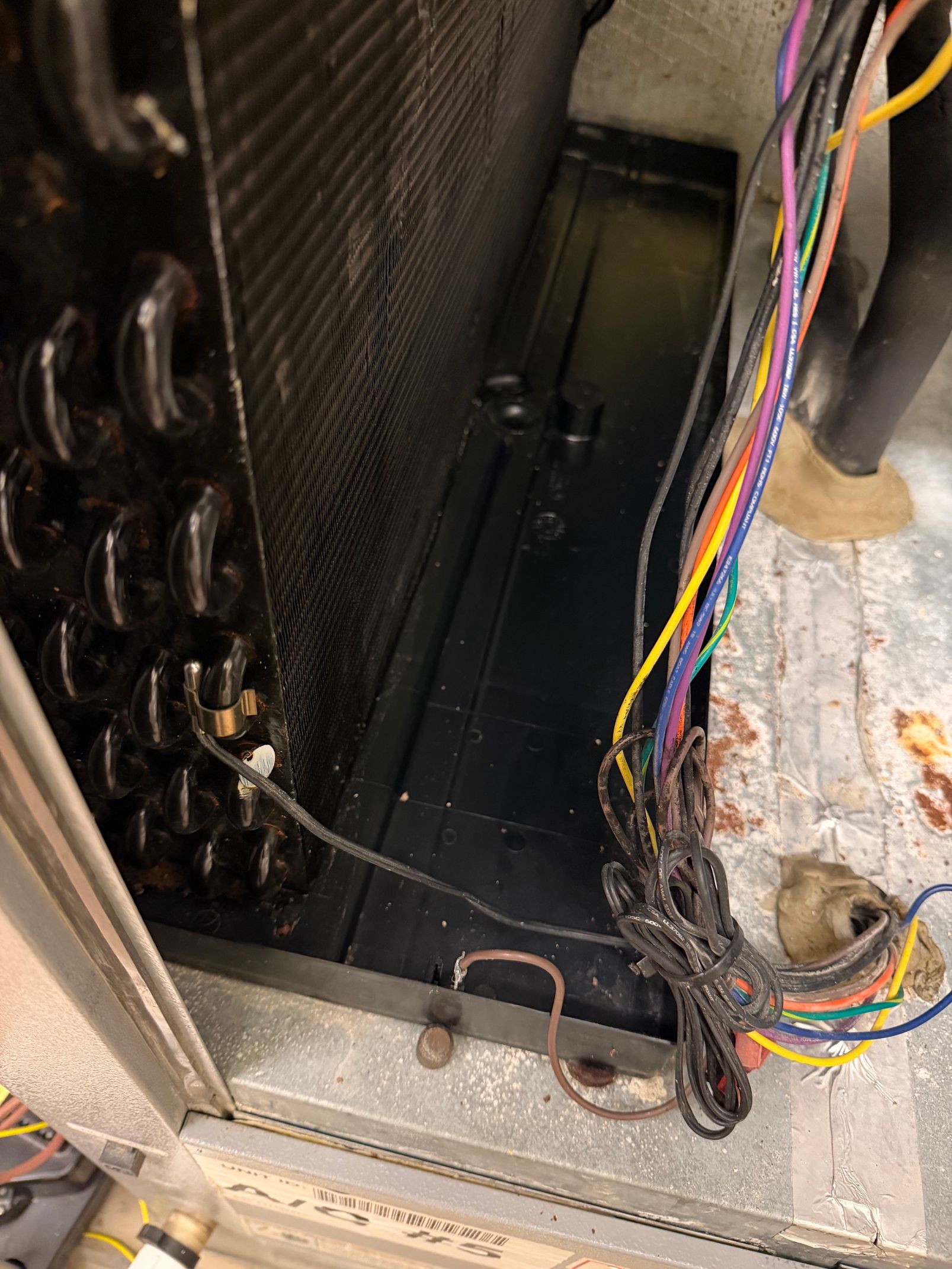 Interior of an appliance with exposed wiring, black panels, and a damaged or unfinished base area.