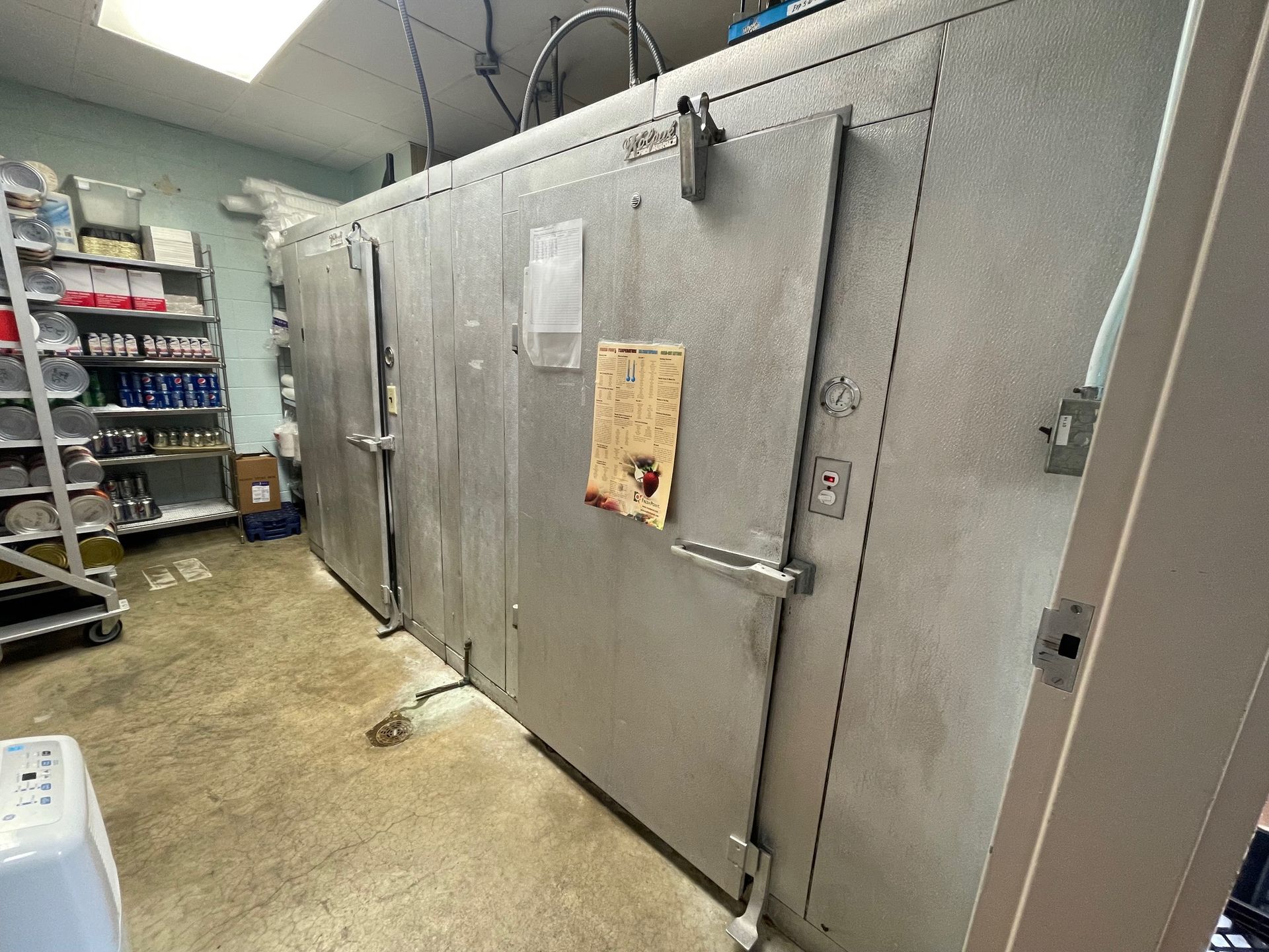 Walk-in cooler with silver metal doors in a commercial kitchen storage room