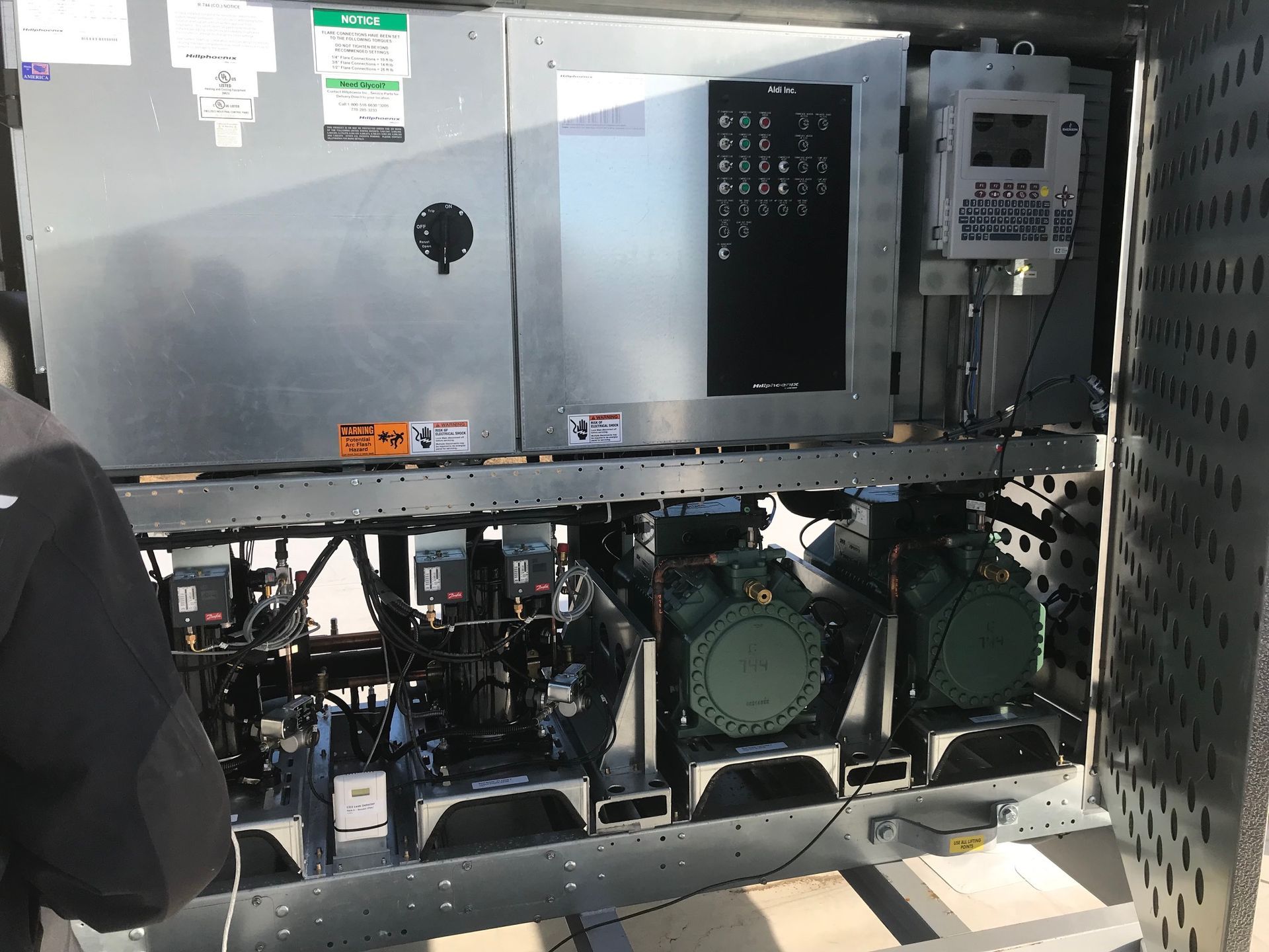 Open machine cabinet with wiring, fans, and control panels inside an industrial setting