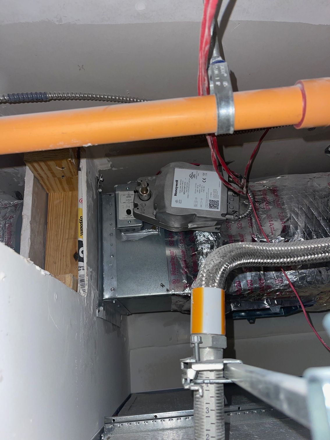 Orange pipe and wiring inside a cramped mechanical ceiling space.
