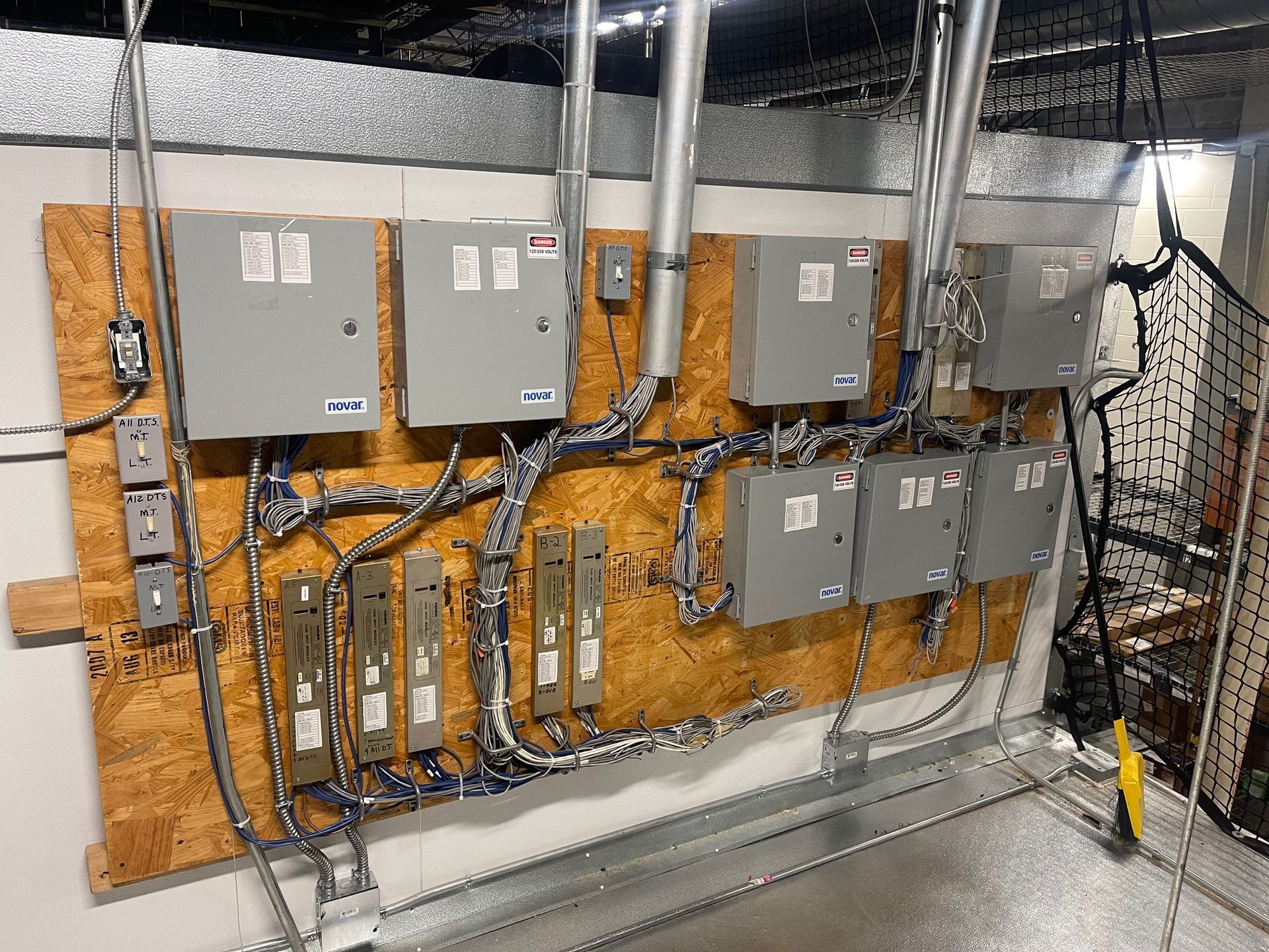 Electrical service panels and wiring mounted on a wooden board in a utility room