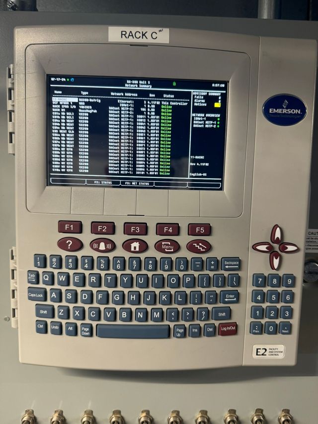 Industrial control terminal with small screen, keyboard, and navigation pad displaying text on a dark interface