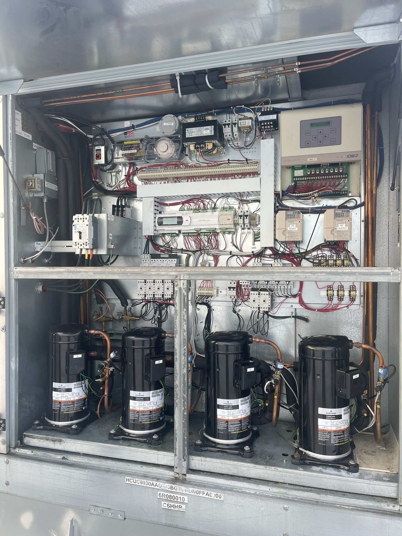 Open electrical control cabinet with wiring, relays, meters, and four large black compressors inside