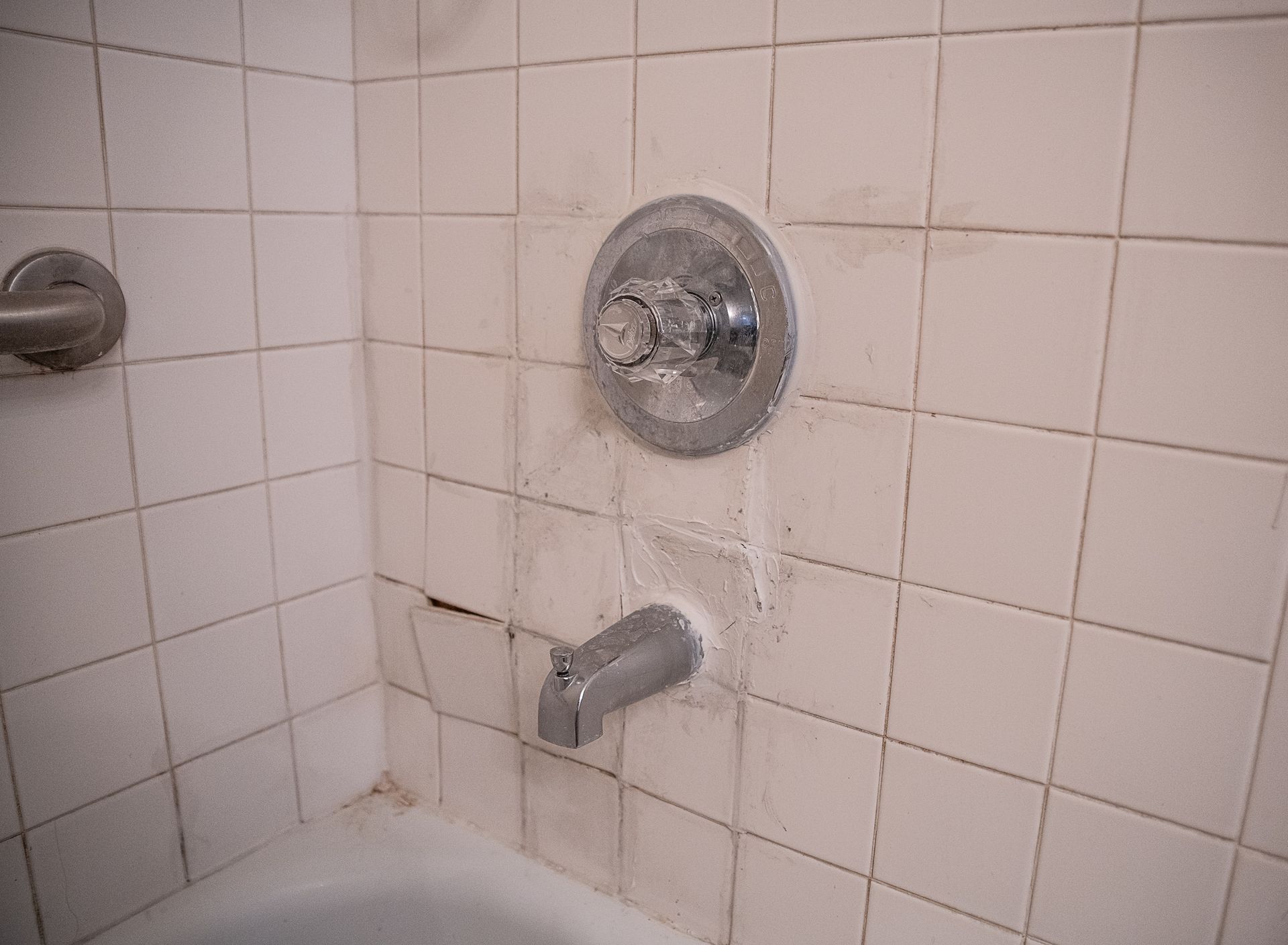 A bathroom with dirty tiles and a bathtub