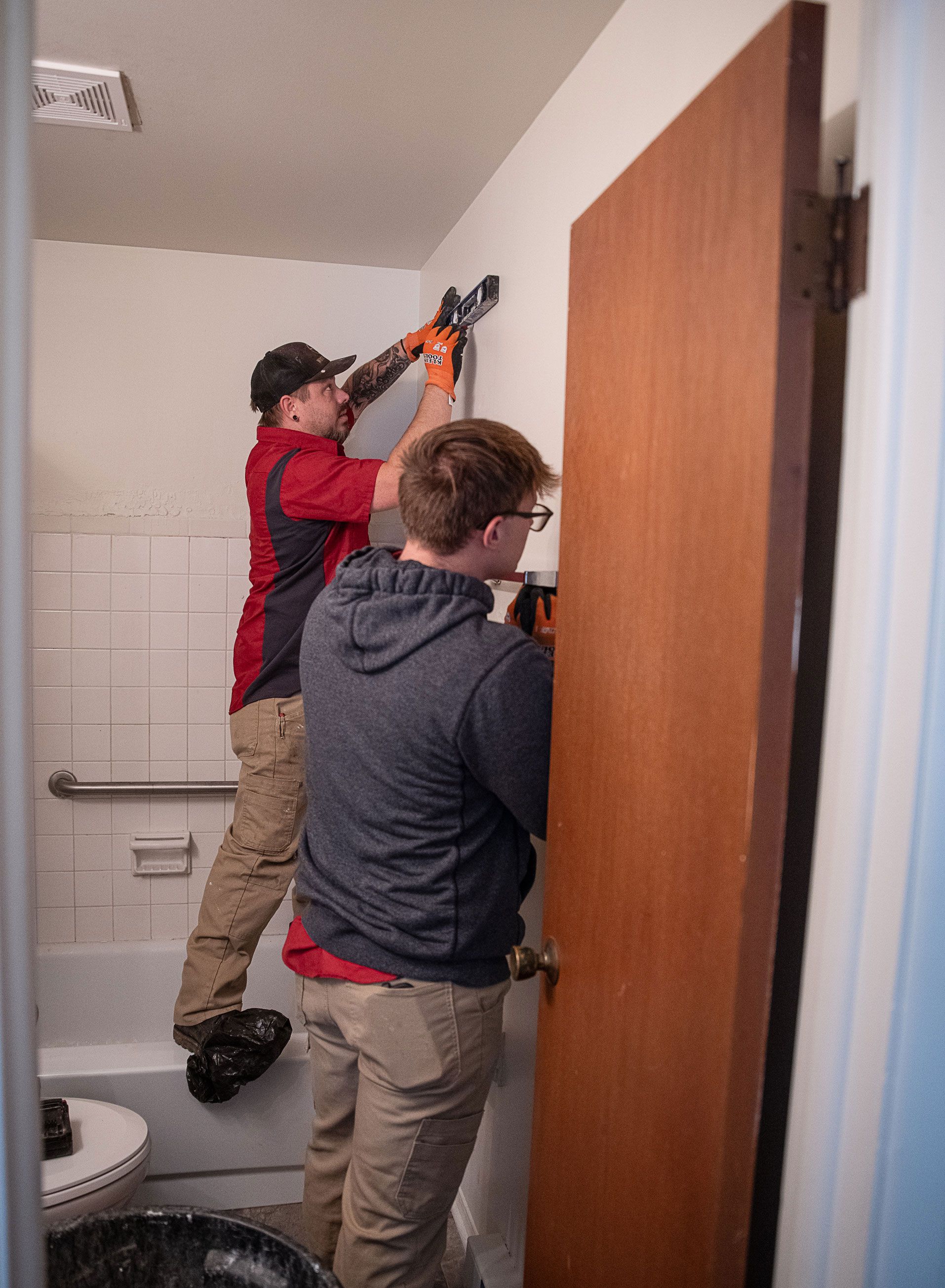 Two men are working on a door in a bathroom