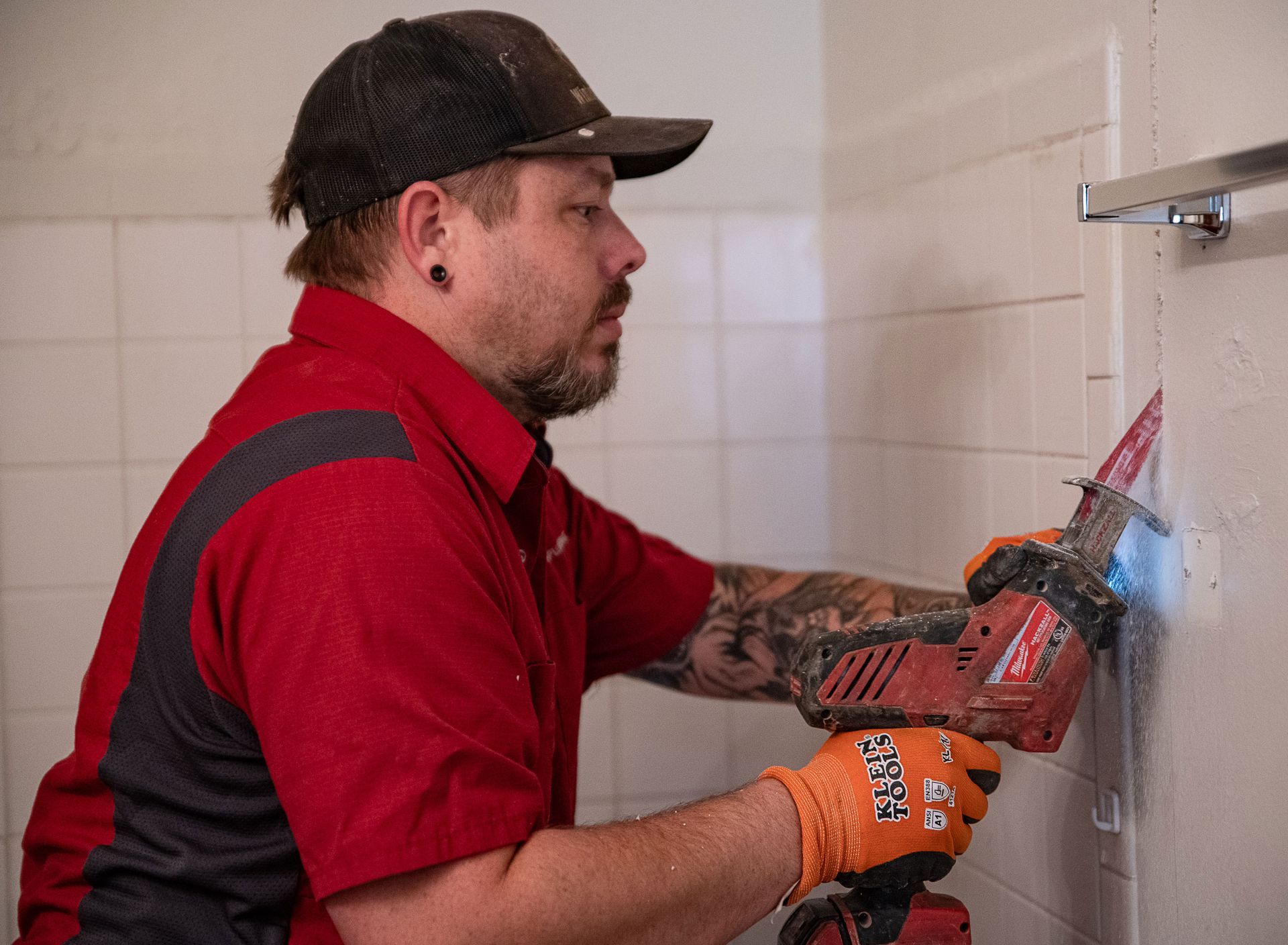 A man is working on a wall with a drill and a saw