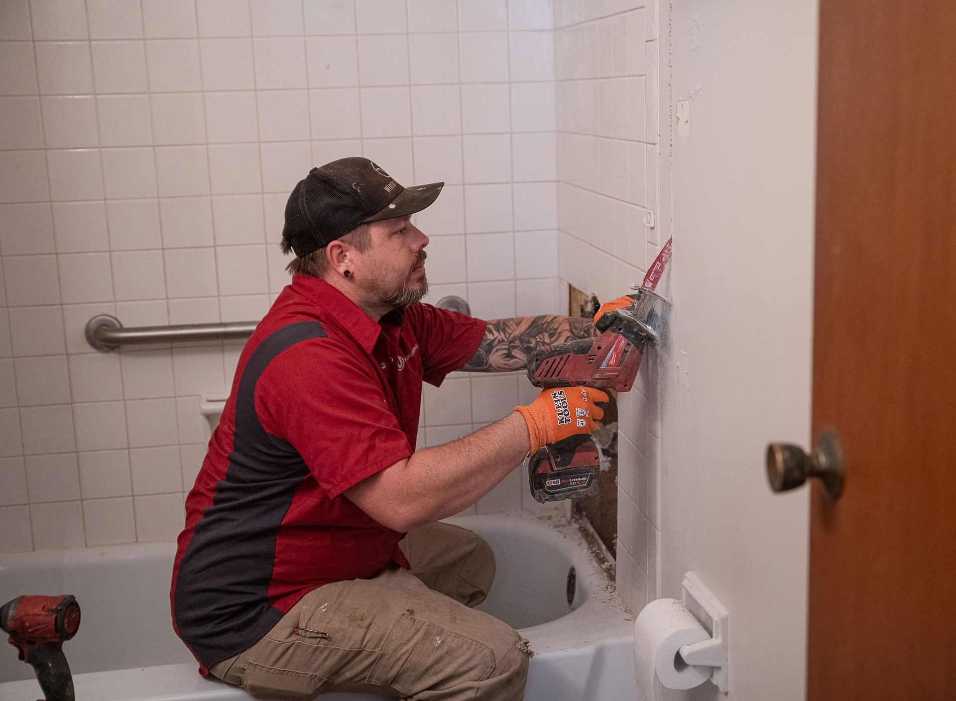 A man is sitting in a bathtub fixing a shower head