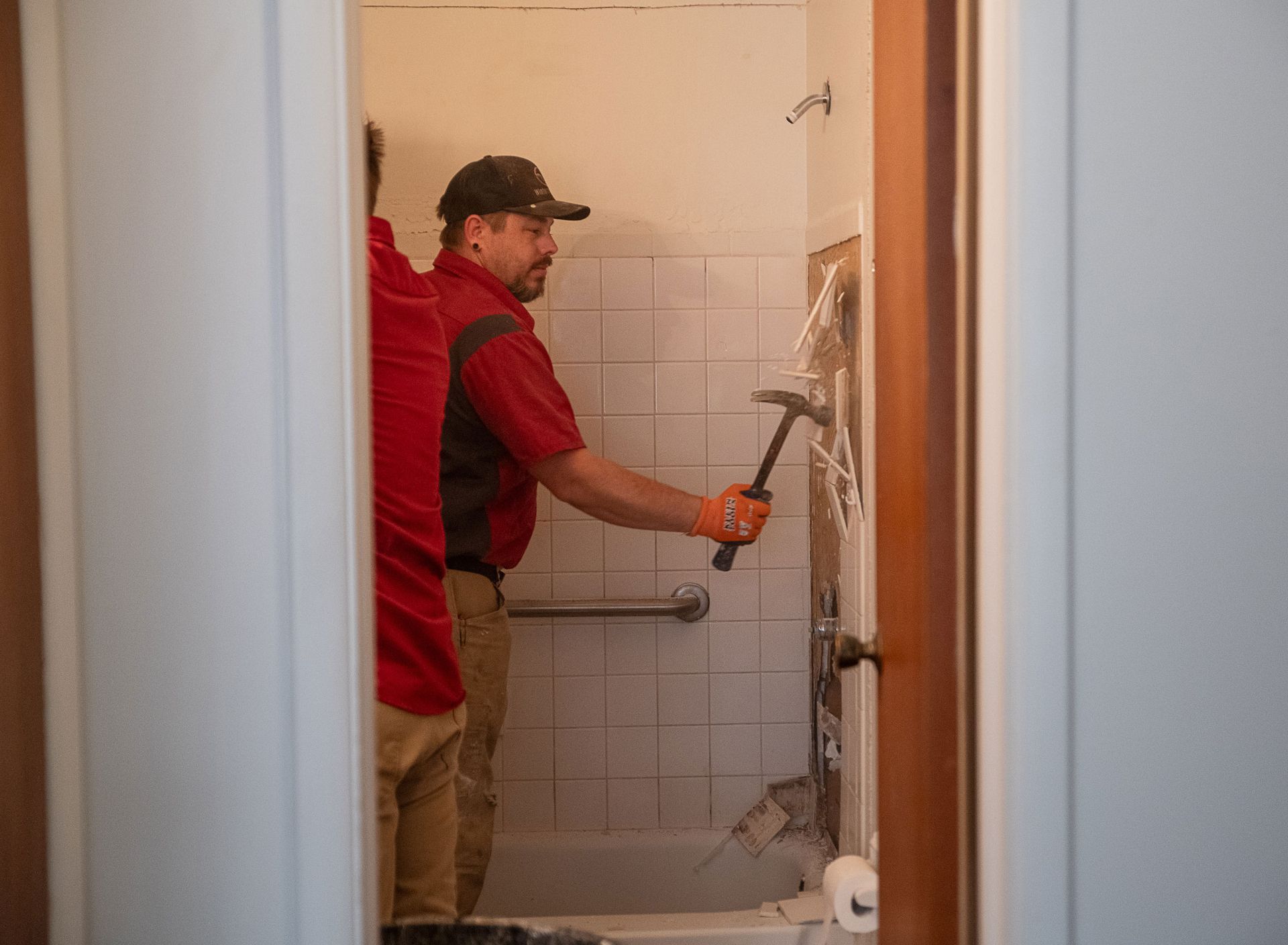 A man is holding a hammer in a bathroom.