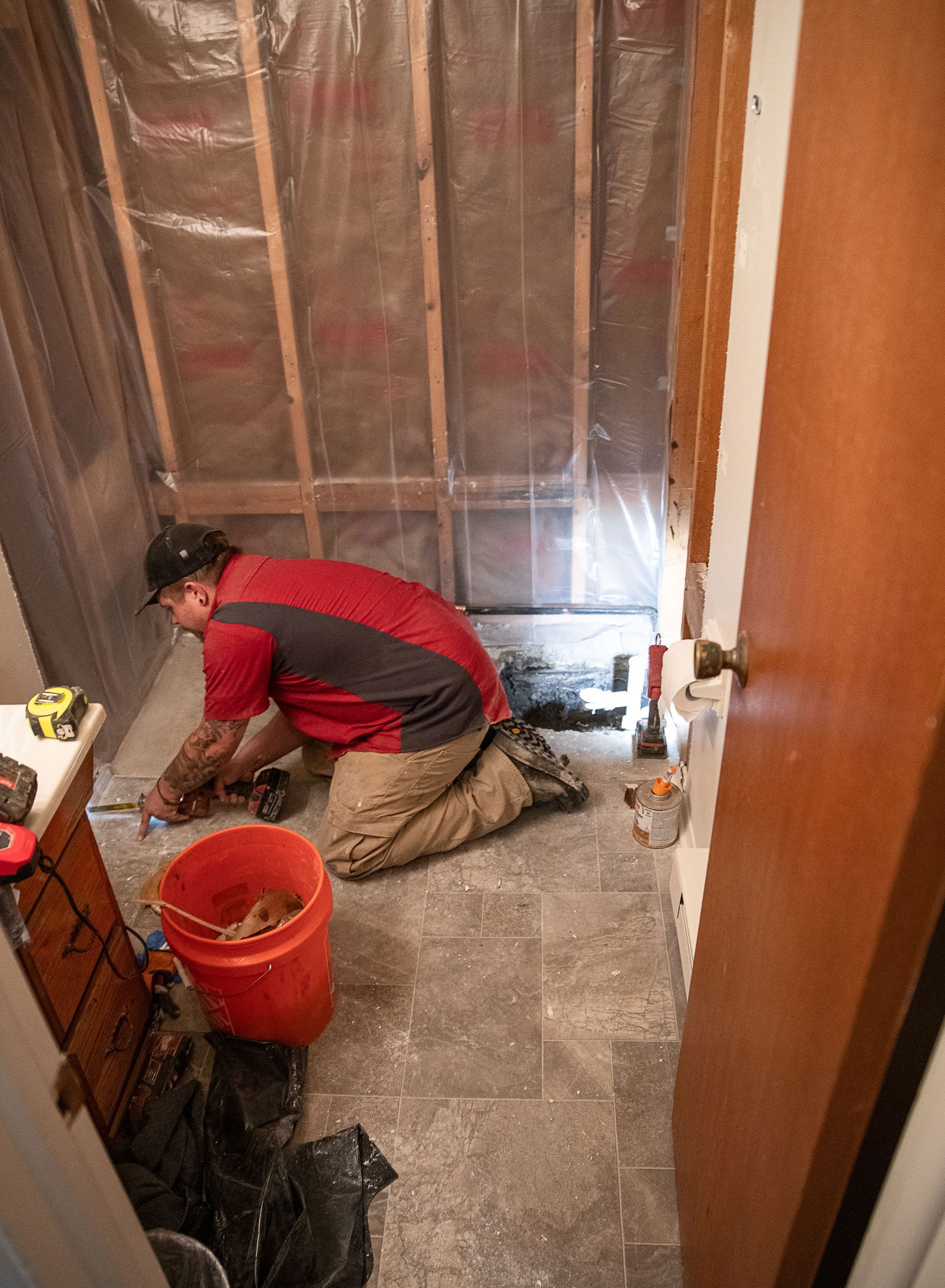 A man is kneeling on the floor in a bathroom