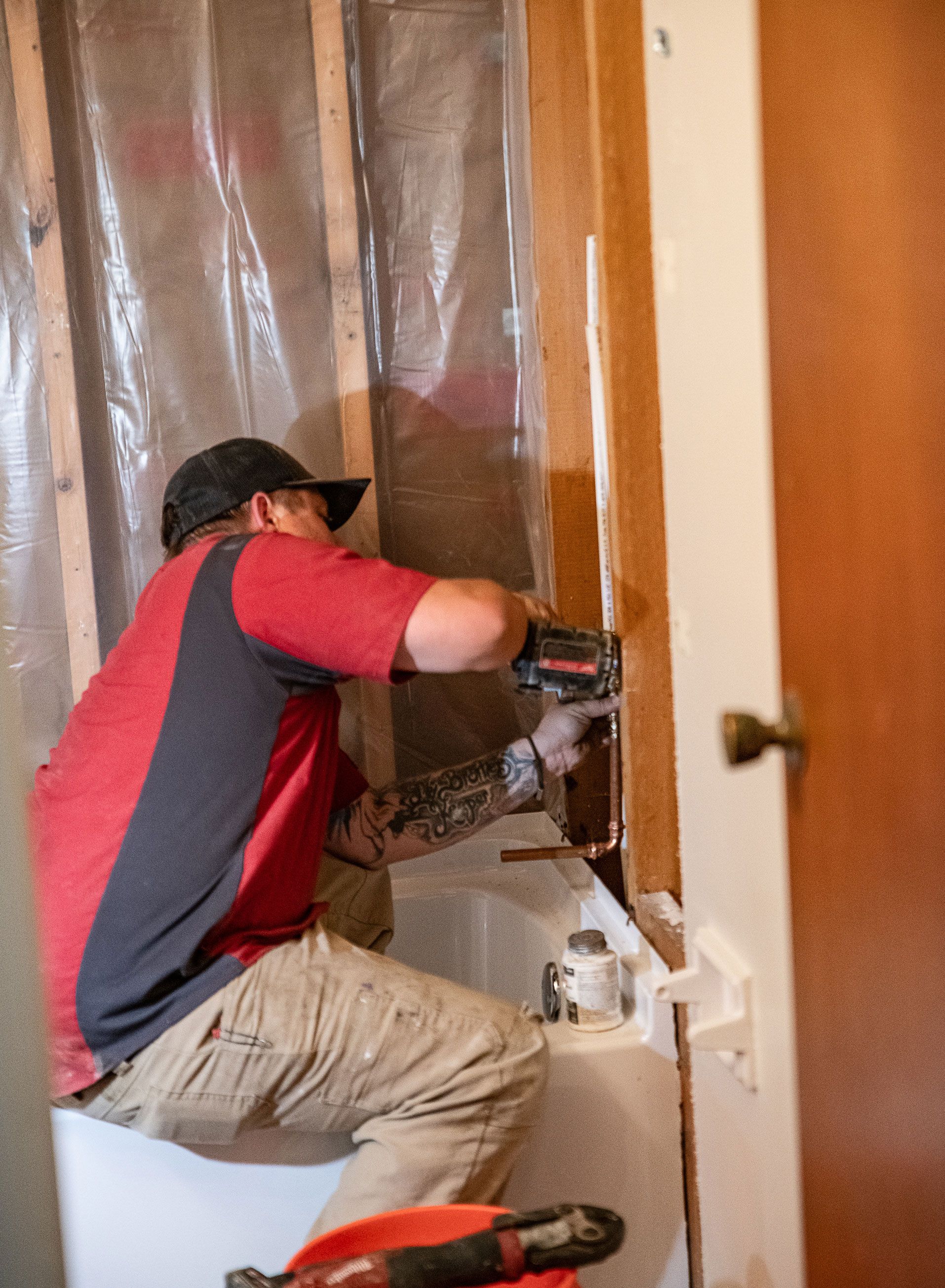 A man is sitting in a bathtub using a drill