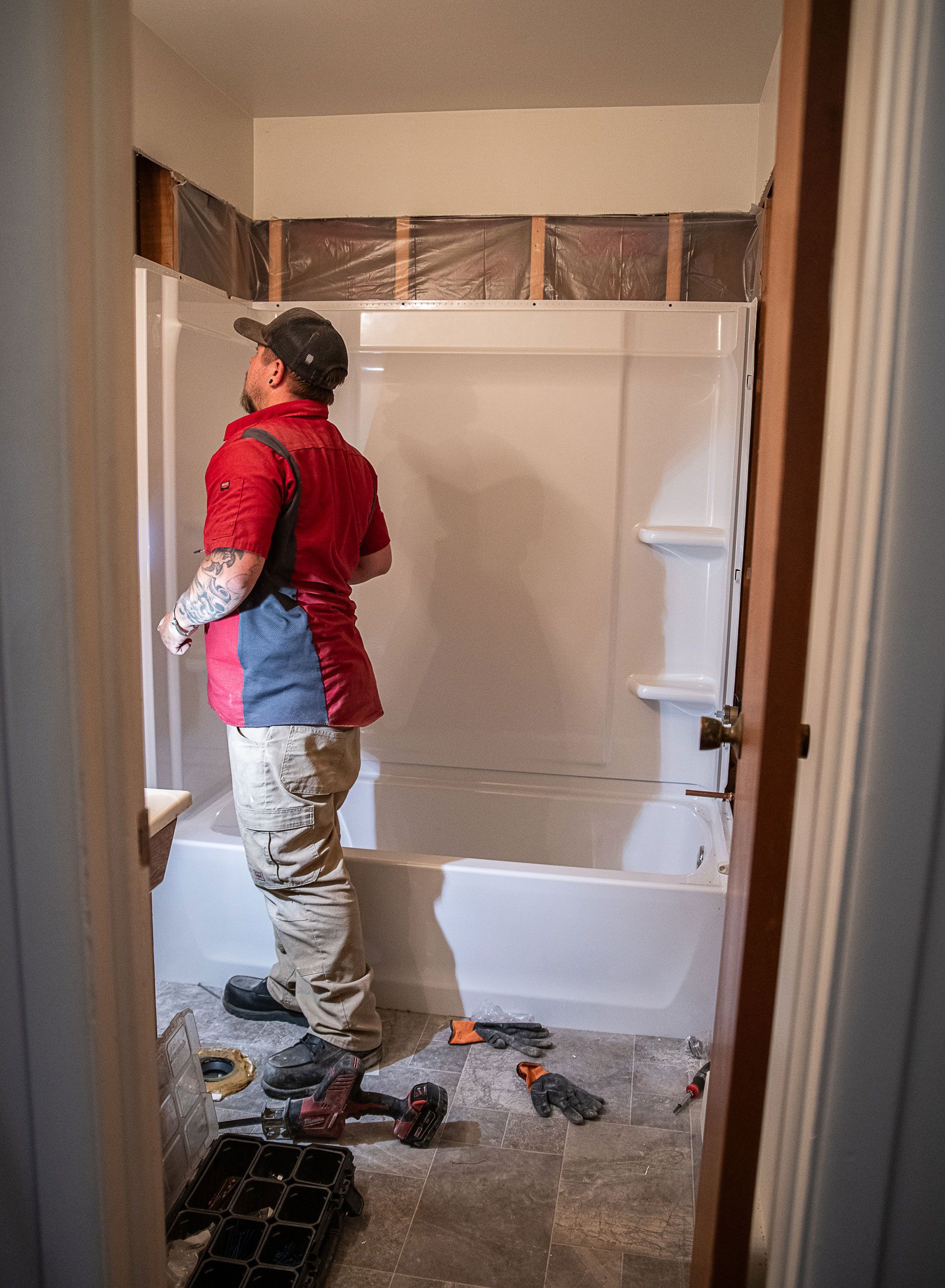 A man is standing in a bathroom next to a bathtub