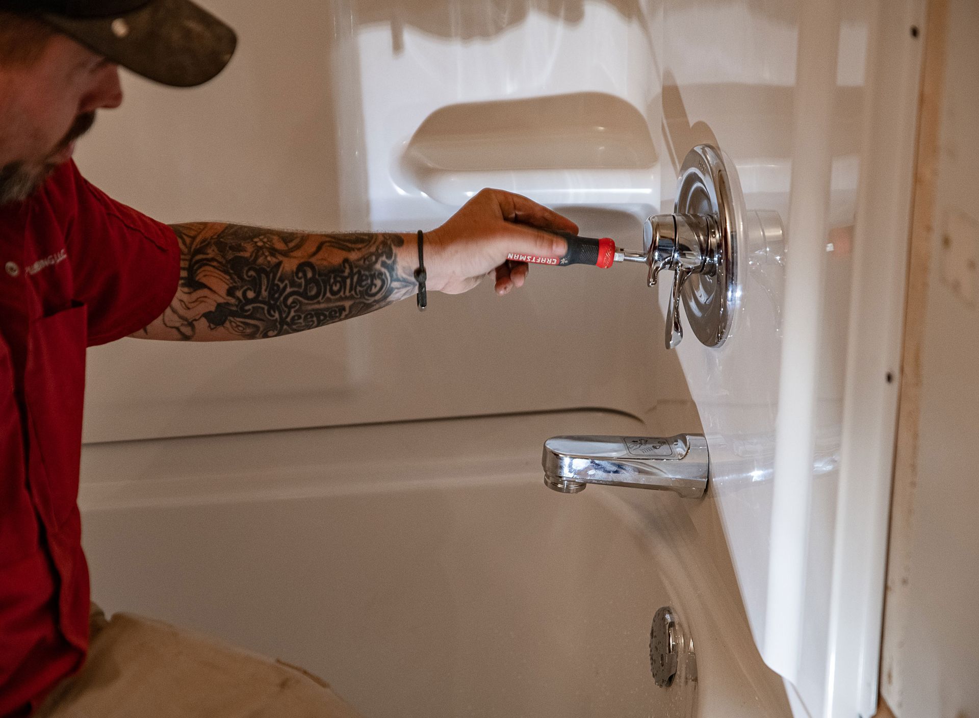 A man is fixing a bathtub with a screwdriver.