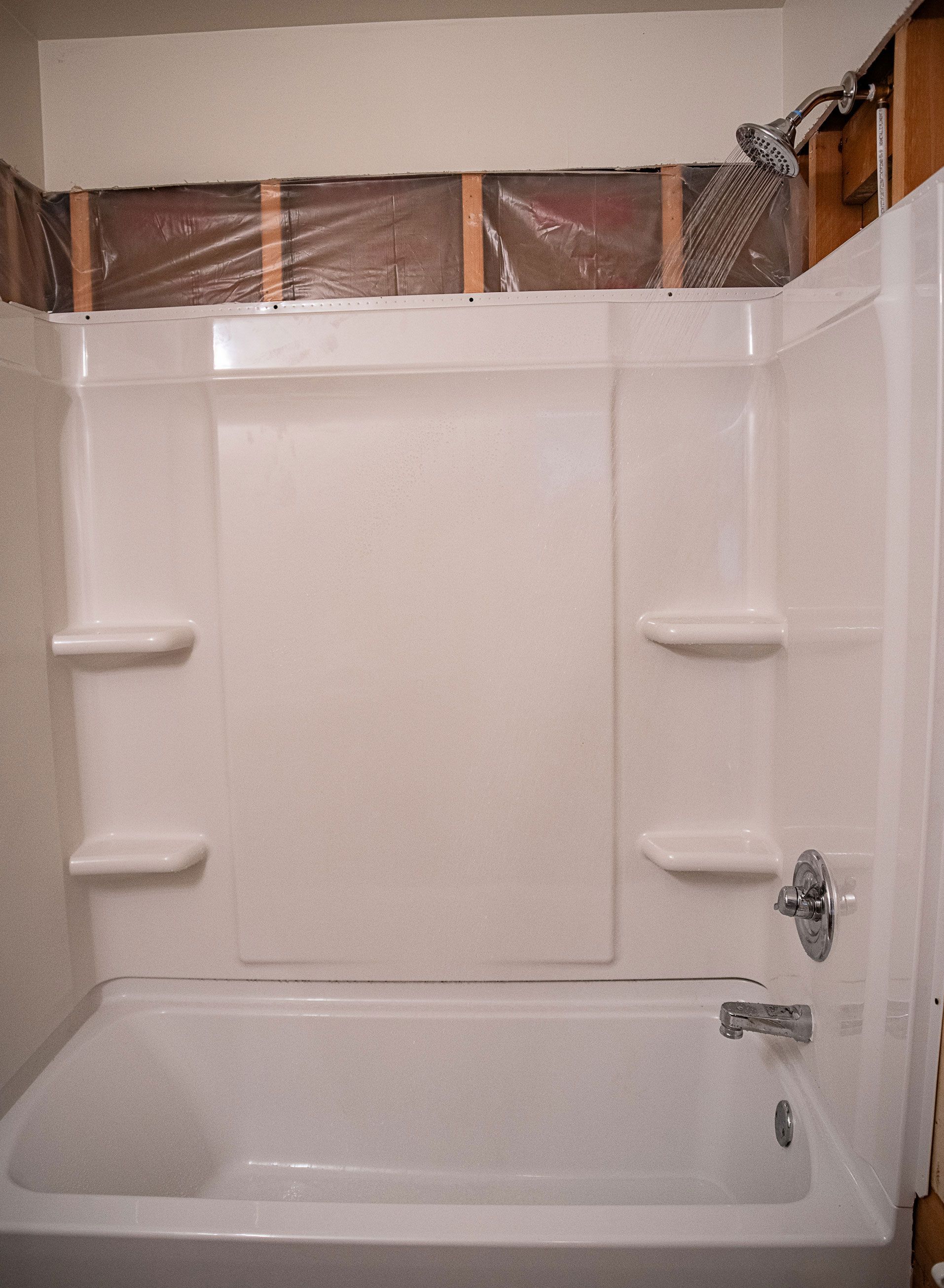 A bathtub with shelves and a shower head in a bathroom