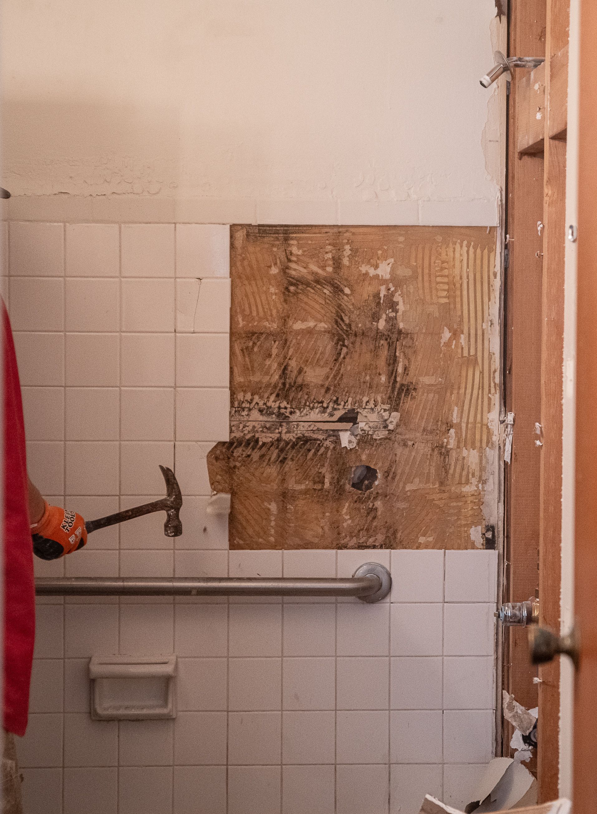 A person is holding a hammer in a bathroom