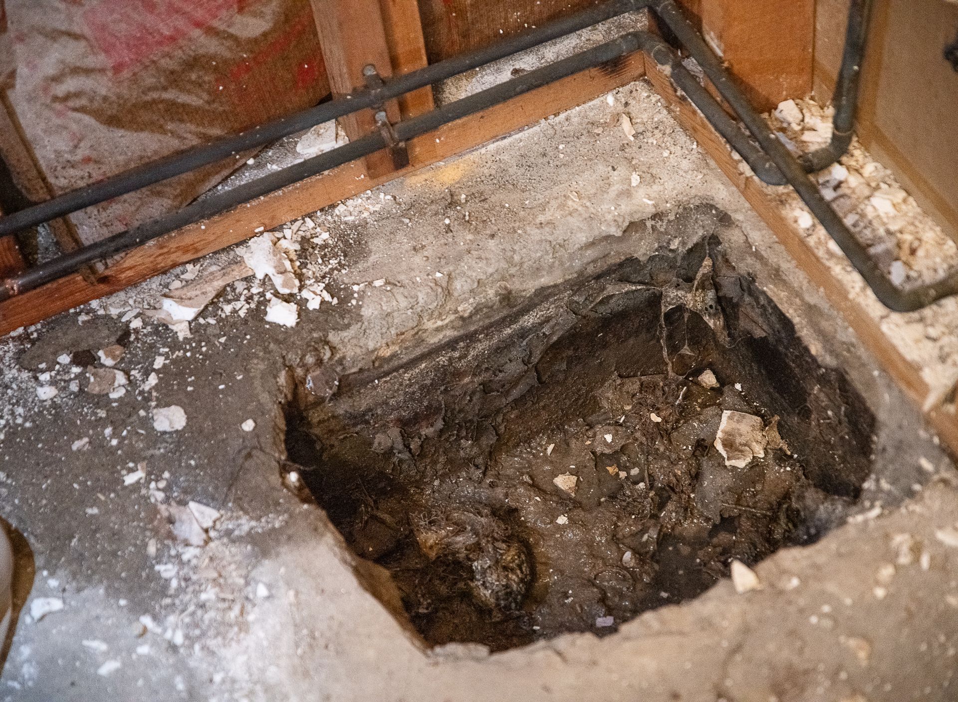 A hole in the floor of a building with pipes coming out of it