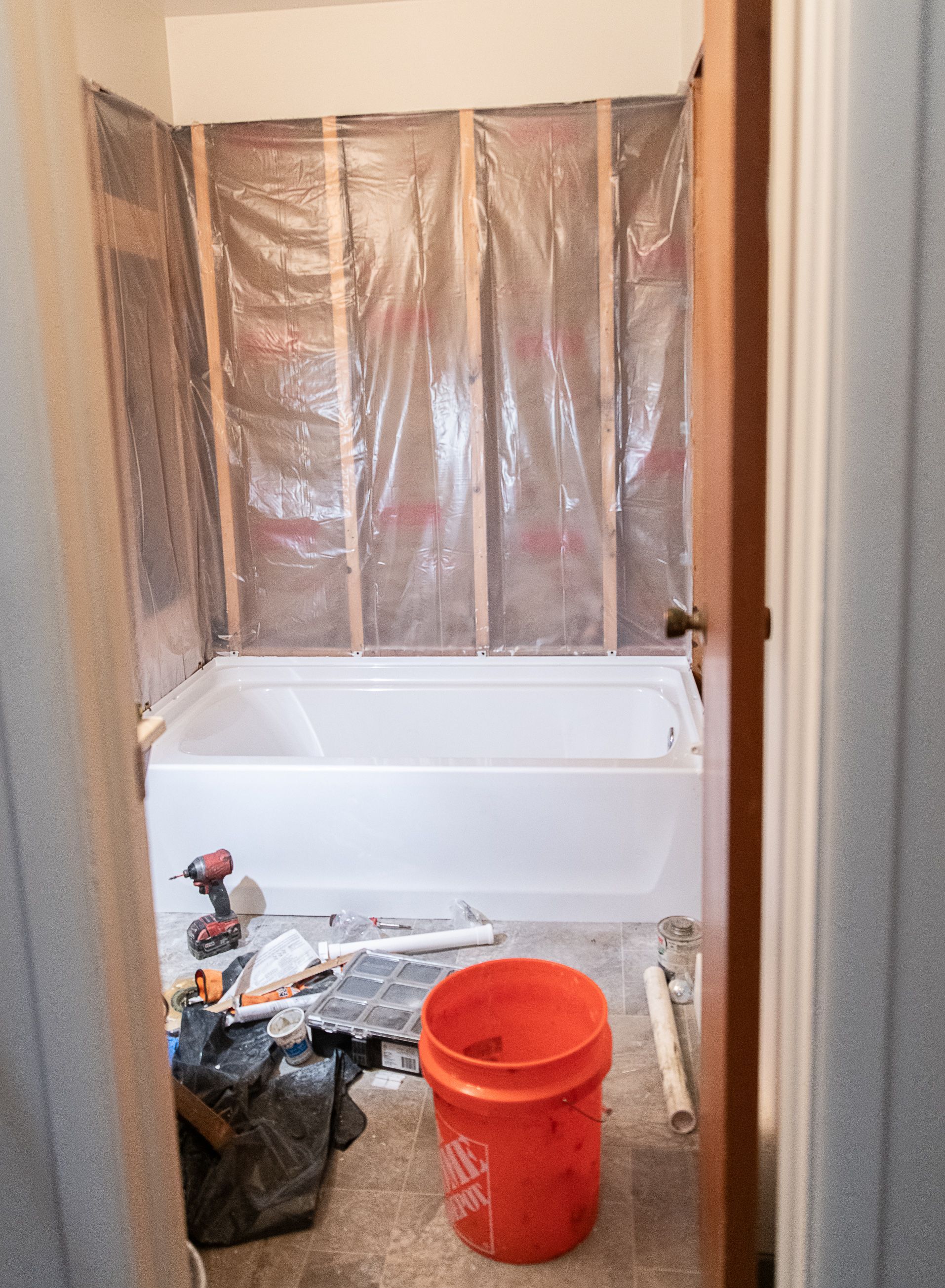 A bathroom under construction with a bathtub and a bucket on the floor