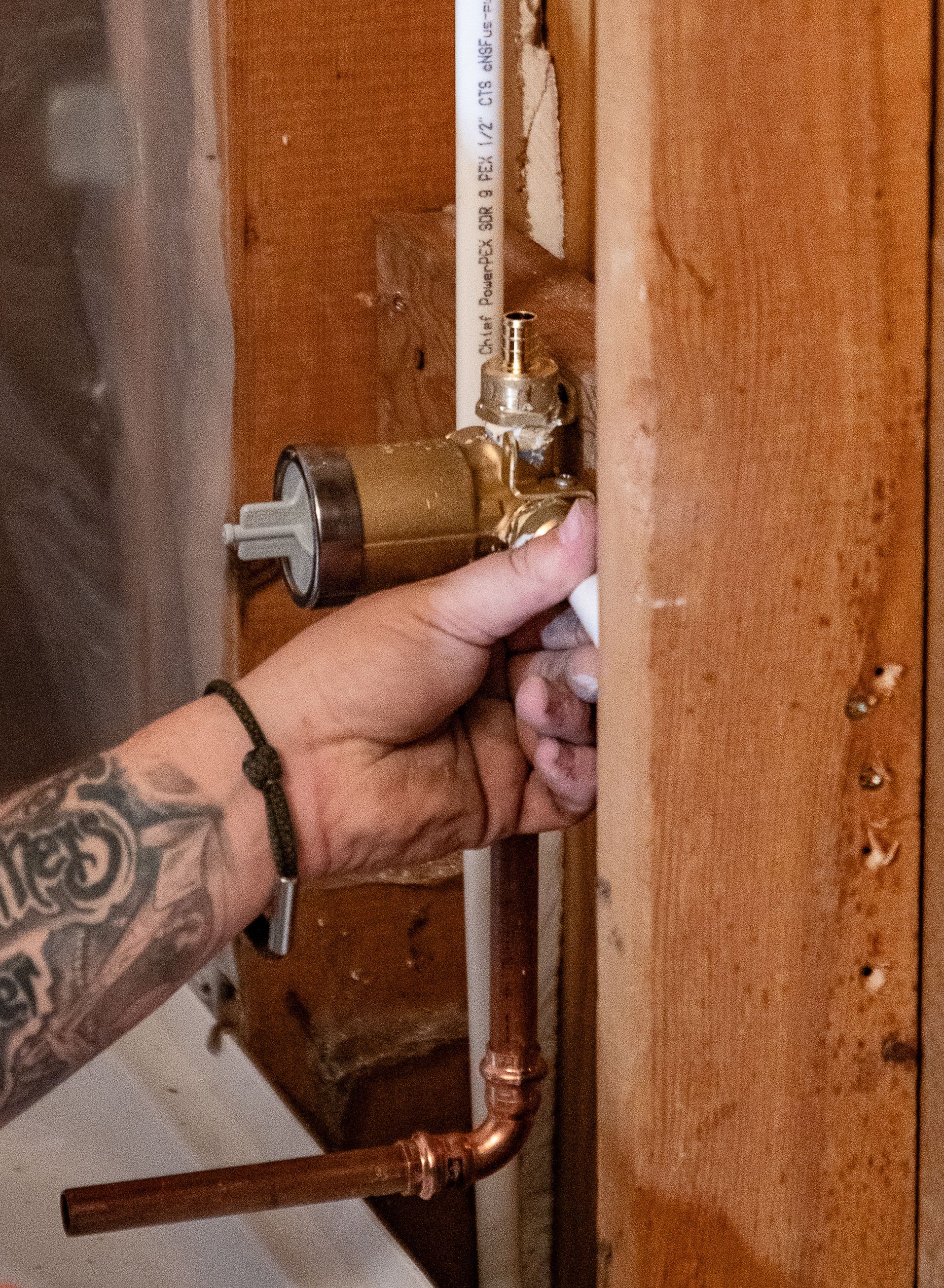 A man with a tattoo on his arm is working on a pipe