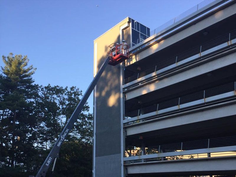 A construction lift reaching towards a multi-level parking garage.
