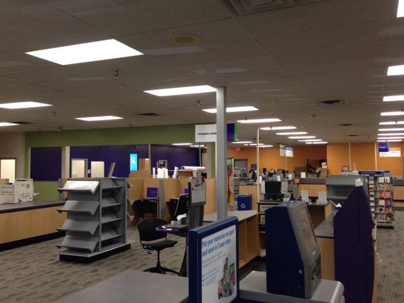 Interior of a library with rows of computers and service desks, fluorescent lighting, and patrons.
