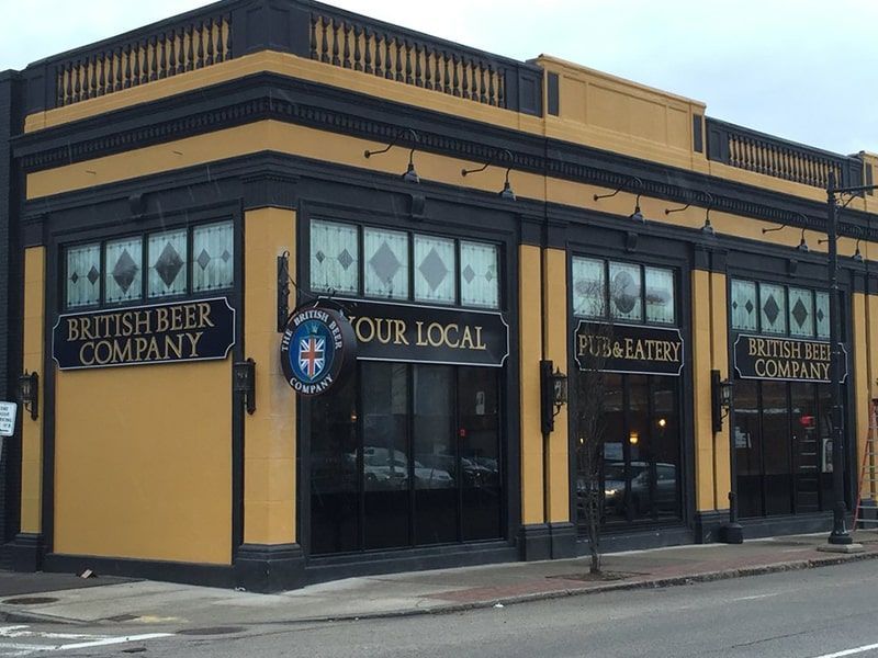 Exterior of a British Beer Company pub with yellow and black facade; corner entrance.