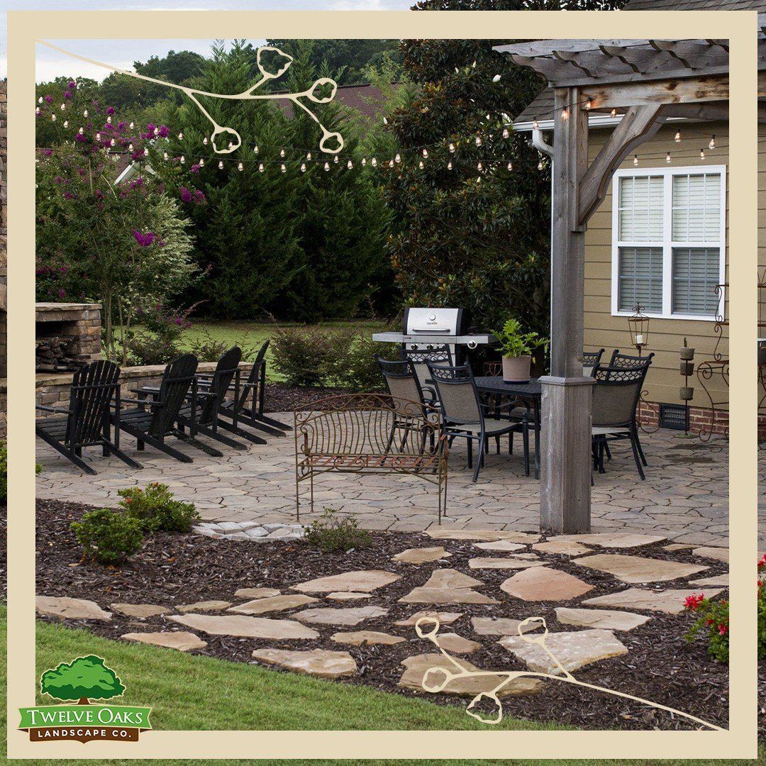 Patio with seating, pergola, grill, and landscape. String lights and stone path.