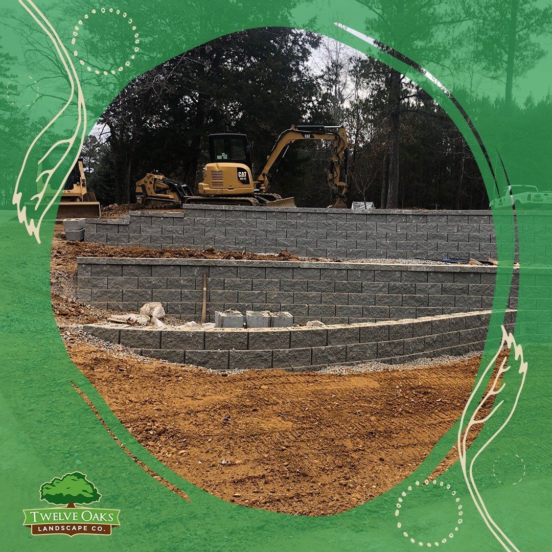 Excavators building a retaining wall in a grassy area; brown soil, gray blocks, green background.