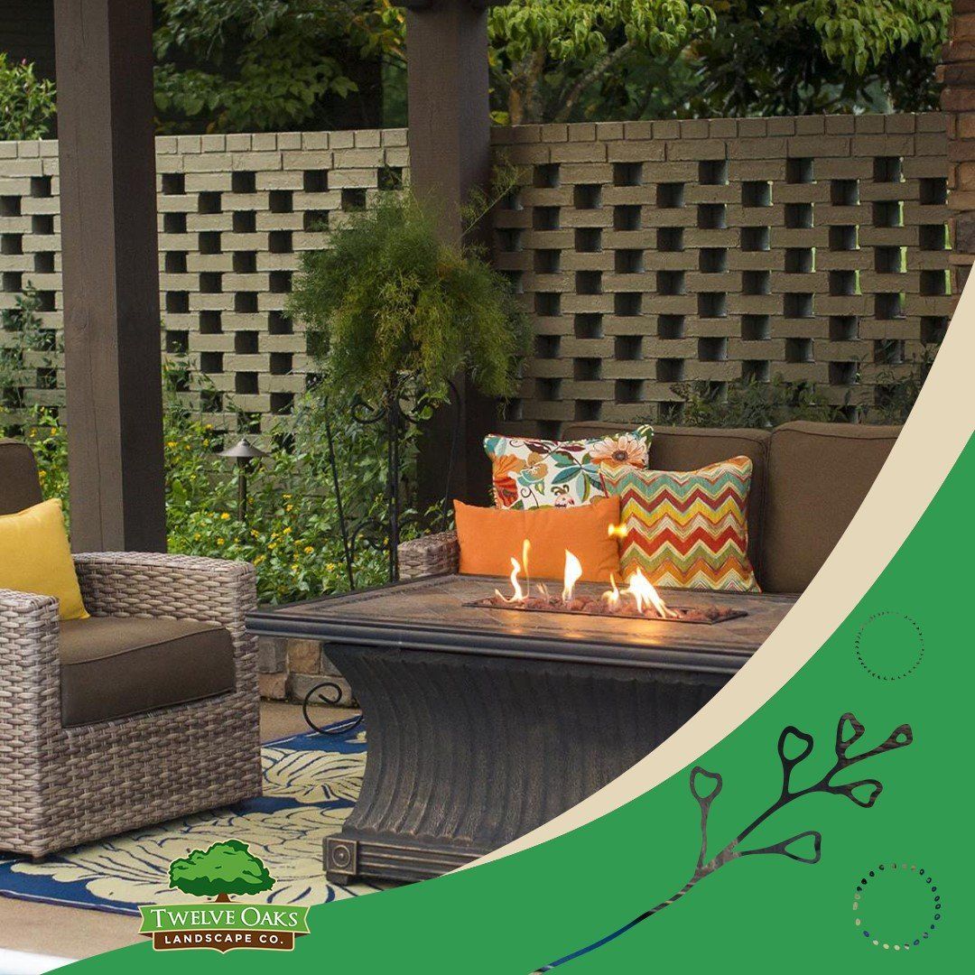 Outdoor patio with seating around a fire table and decorative brick wall.