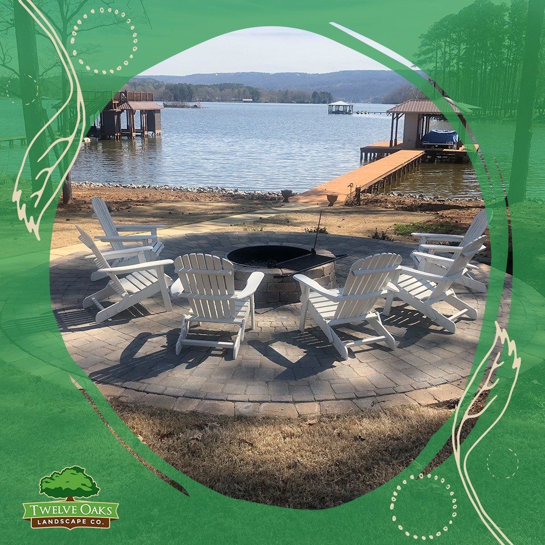 Fire pit with white chairs on a lakeside patio.