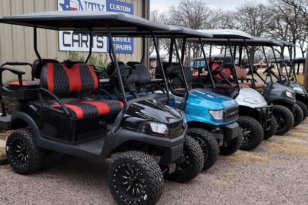 A row of golf carts are parked in front of a building.